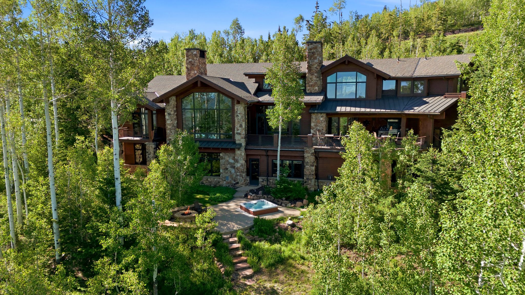 Multi-level residence featuring stone accents, a deep brown facade, and a large window wall