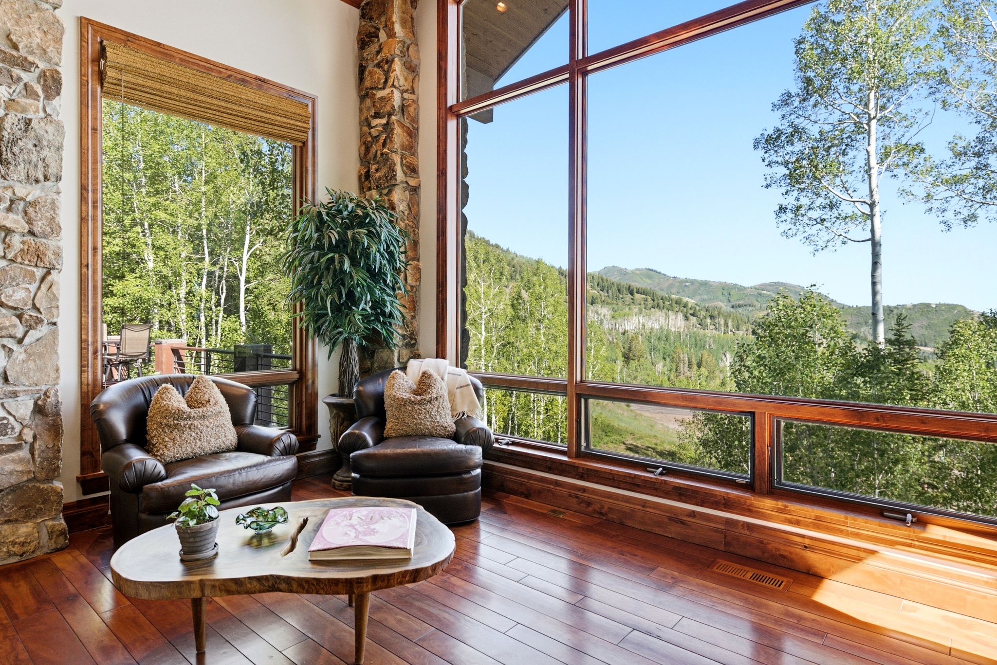 Expansive floor-to-ceiling windows with wood framing offer broad outdoor scenery