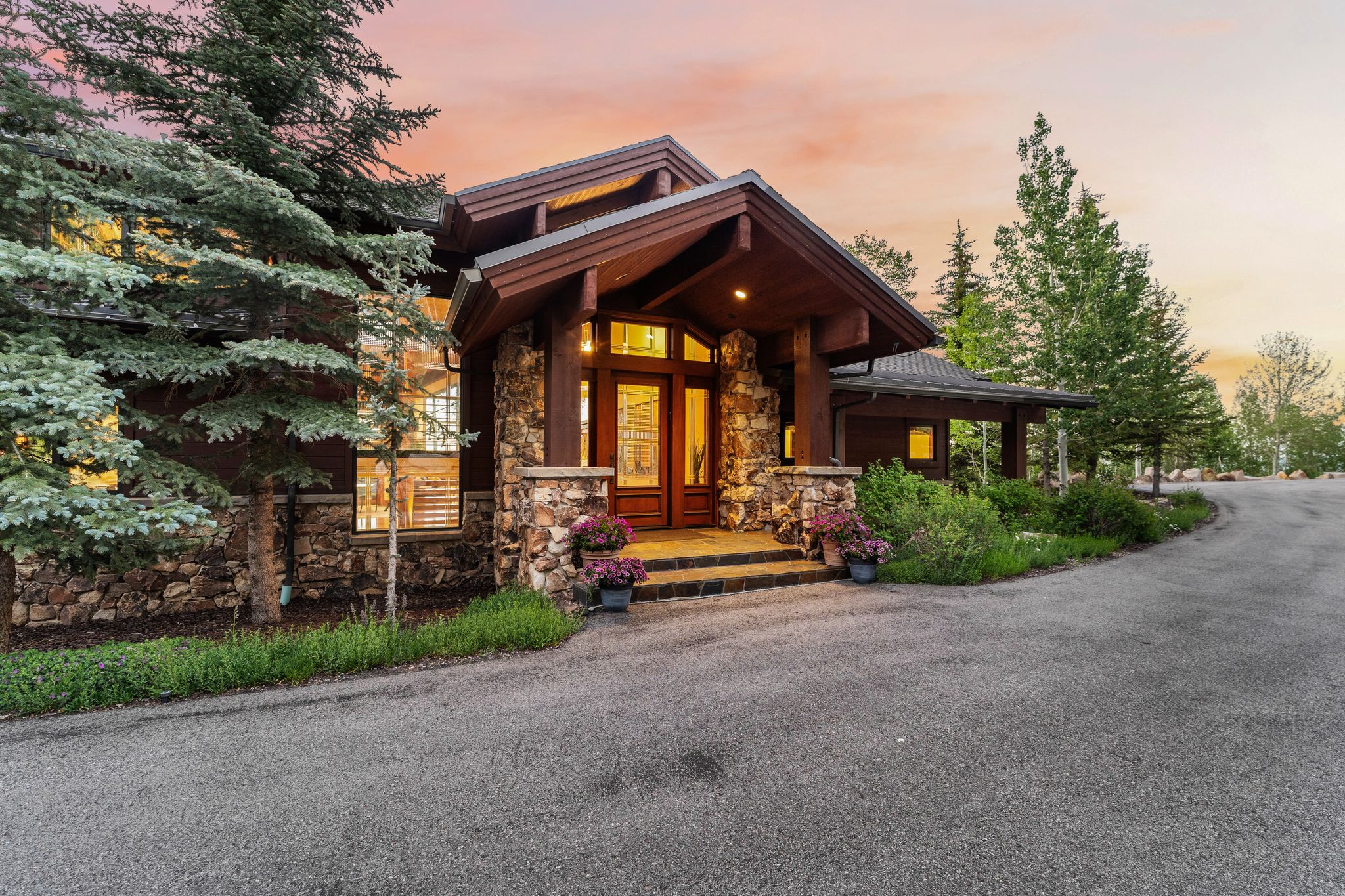 Crafted exterior featuring stone columns, wood-paneled eaves, and a covered entry