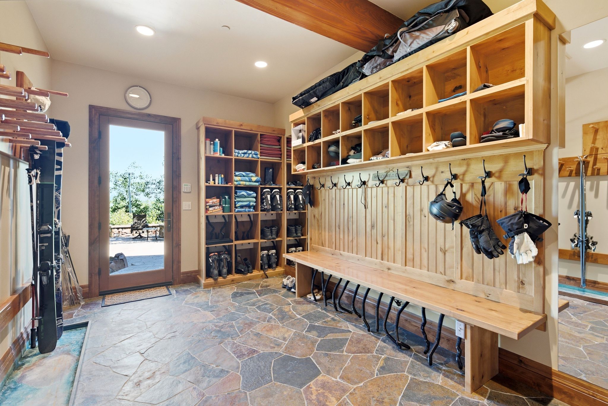Mudroom featuring flagstone flooring, solid wood built-in storage cubbies, a built-in bench with metal boot dryers, and a full-light exterior door