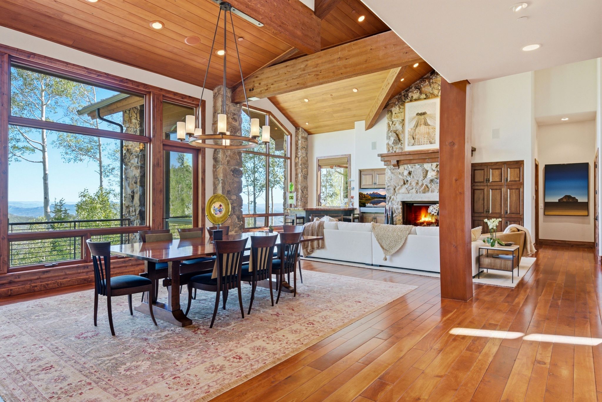 Spacious dining area featuring expansive windows, wood-finish flooring, and a substantial chandelier