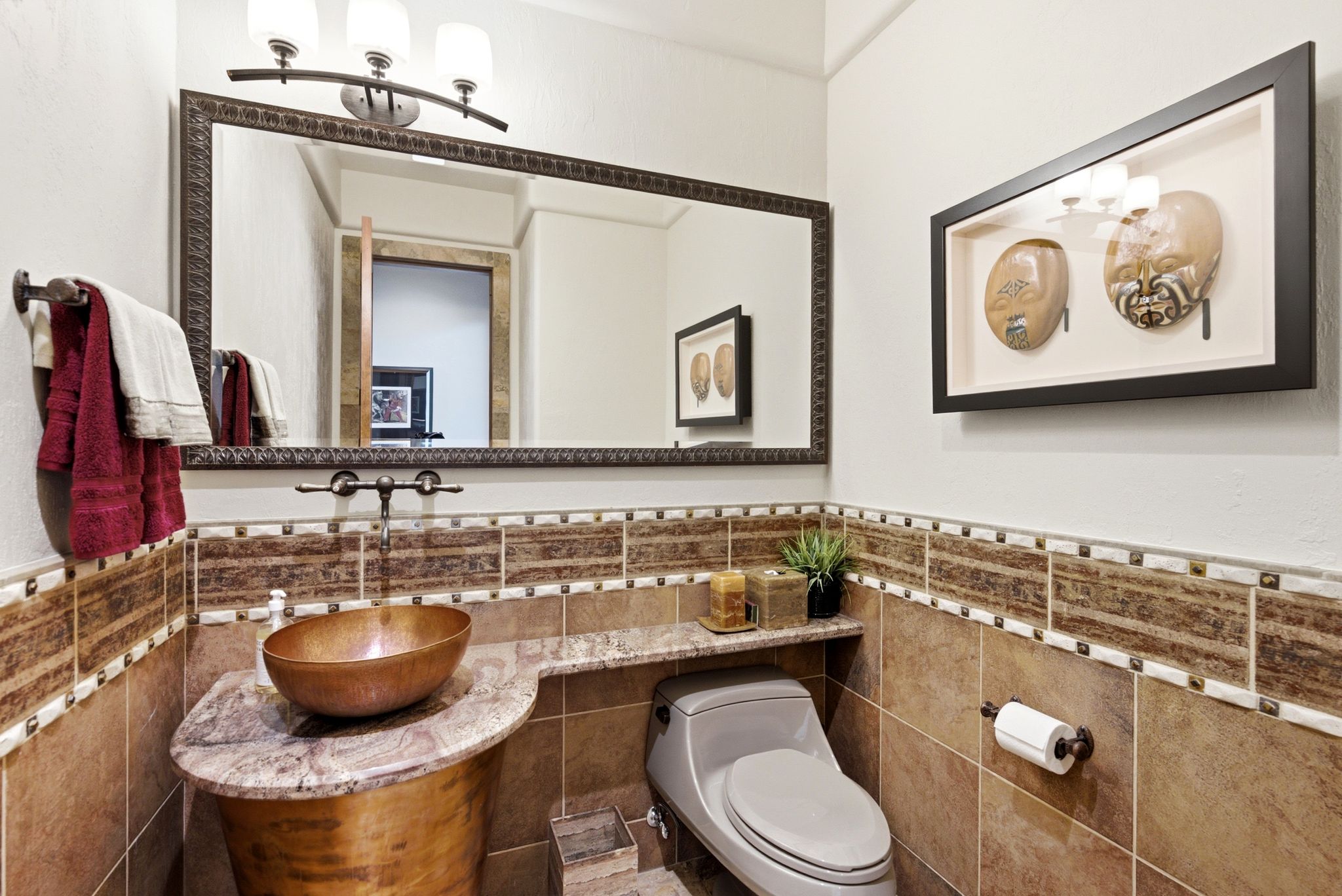 Powder room featuring a vessel sink set on a stone countertop, a wall-mounted faucet, and a large framed mirror