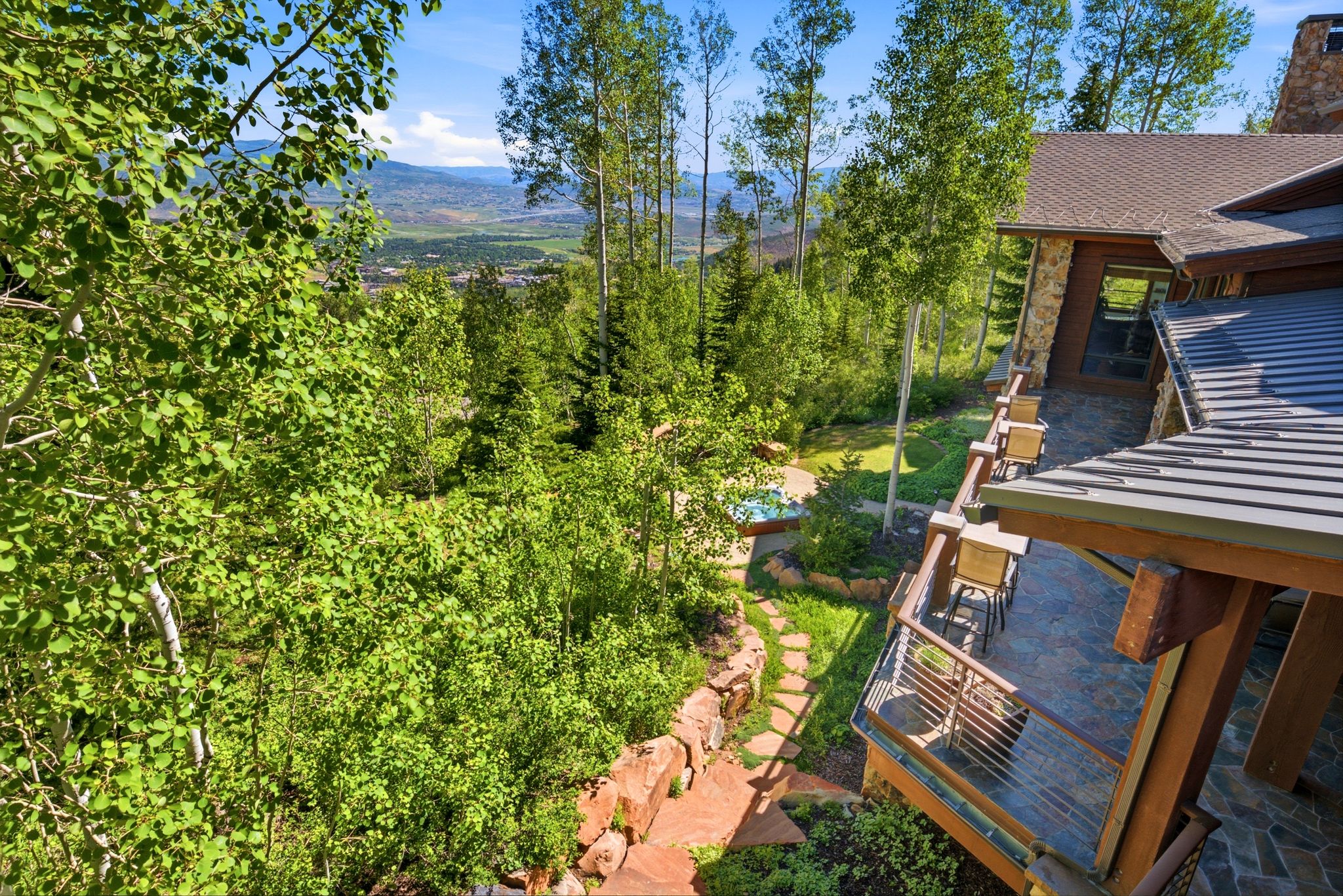 Stone and wood-clad exterior with a multi-level deck featuring a metal railing system
