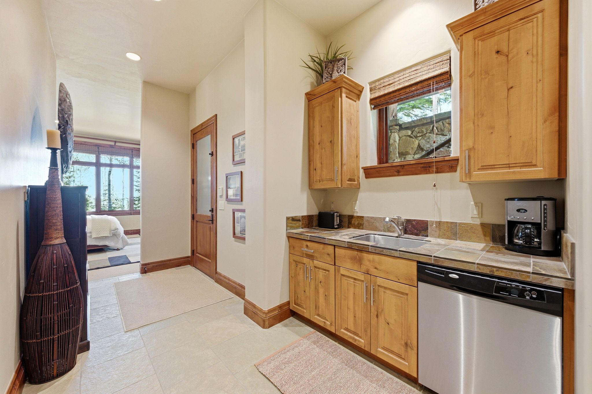 Compact kitchenette featuring light wood cabinetry, a stainless steel sink, and a stainless steel dishwasher