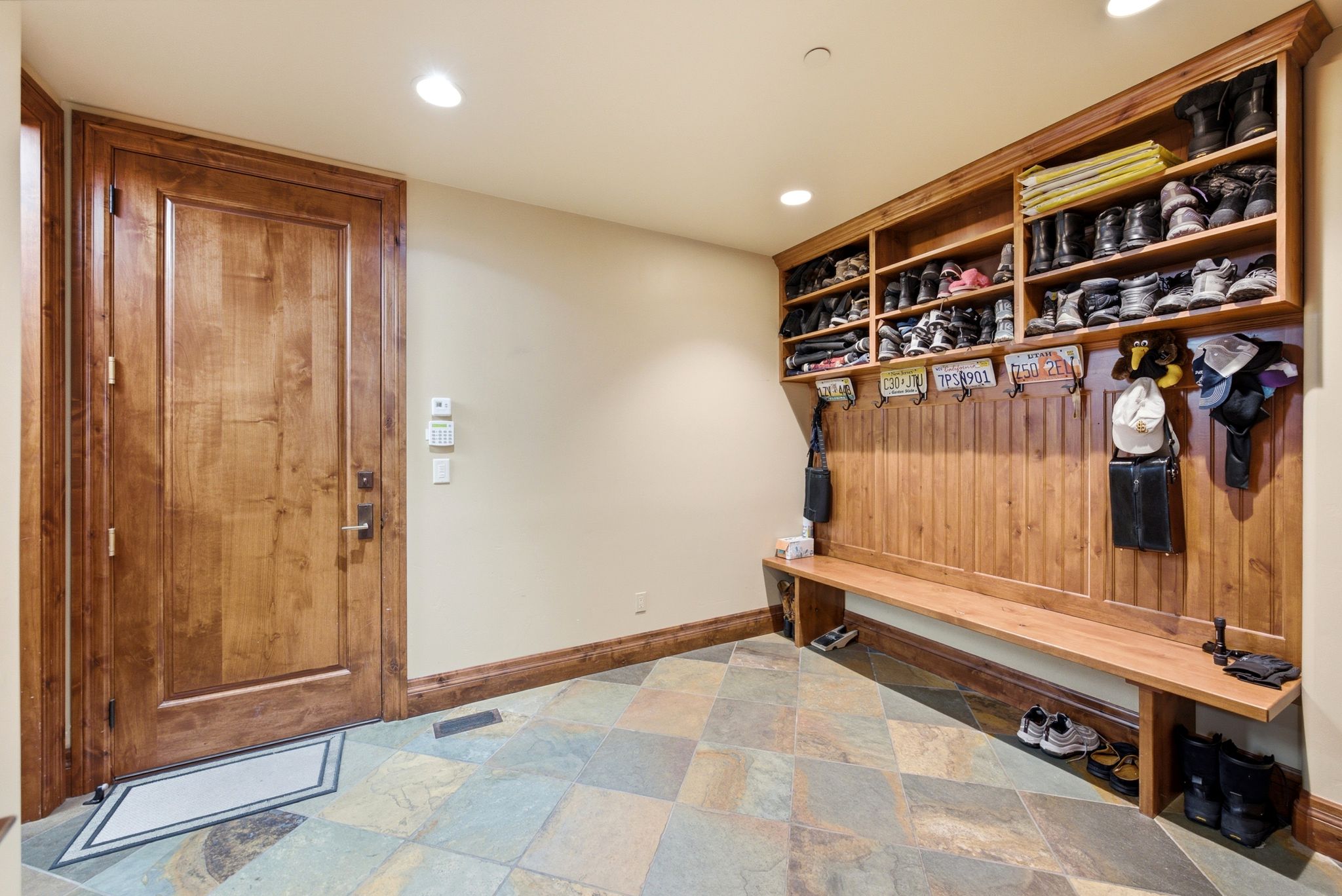 Mudroom featuring extensive built-in storage, a wood-finish bench, and multiple coat hooks