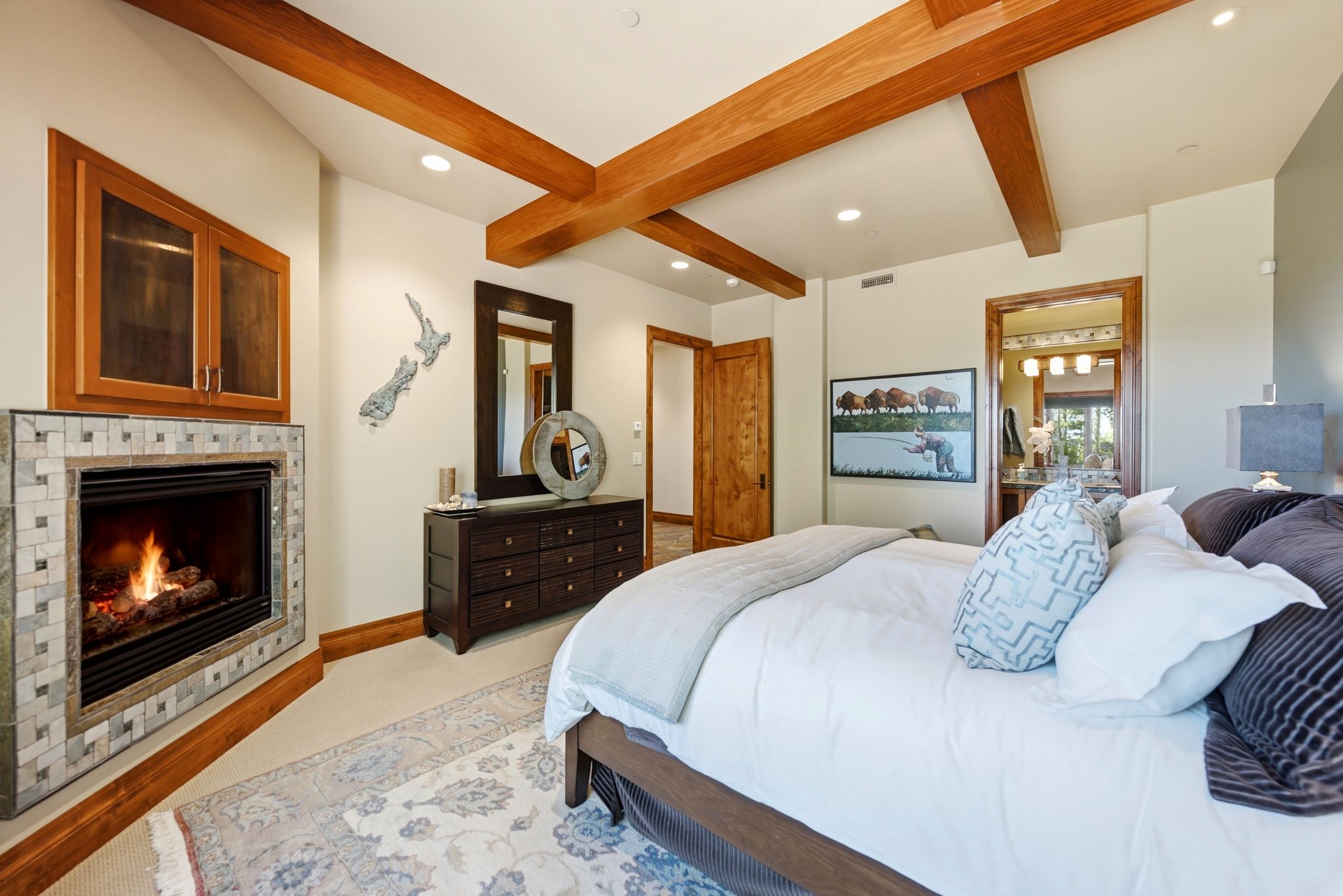 Bedroom featuring a tiled fireplace with wood mantel, exposed ceiling beams, recessed lighting, and a wood-paneled door