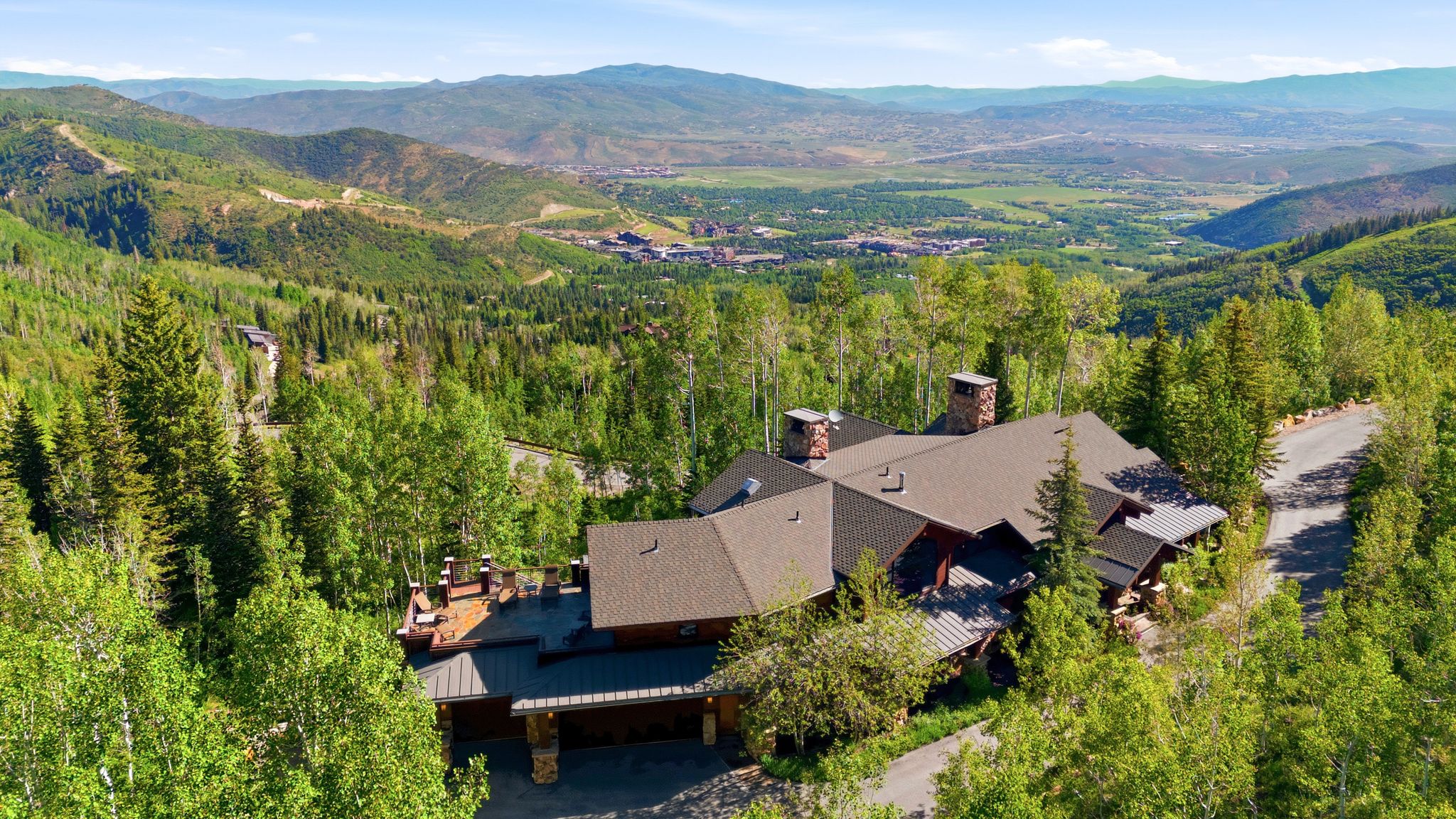 Sprawling mountain-side residence featuring a multi-level roofline and natural stone chimneys