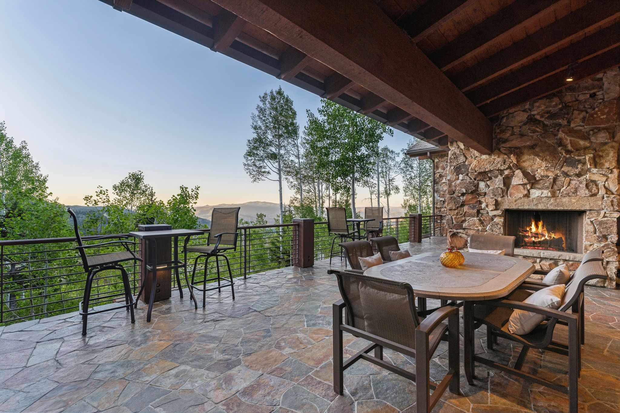 Expansive flagstone patio with a stone-clad fireplace and wood-beamed ceiling