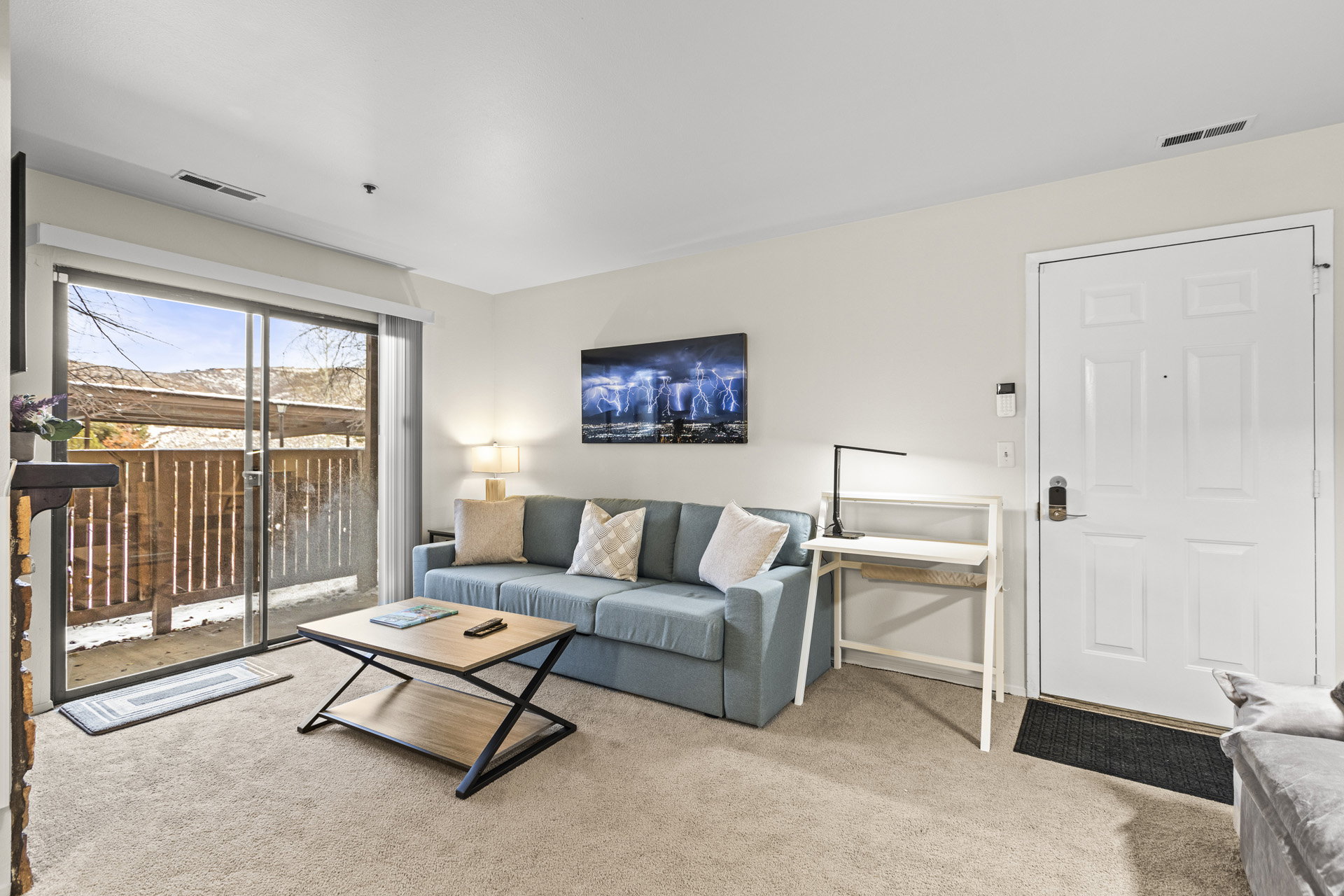 Carpeted living area featuring a sliding glass door to an outdoor patio, neutral wall paint, and a white paneled entry door