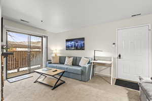 Carpeted living area featuring a sliding glass door to an outdoor patio, neutral wall paint, and a white paneled entry door
