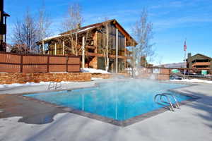 Outdoor swimming pool with concrete surround, featuring stainless steel ladder access