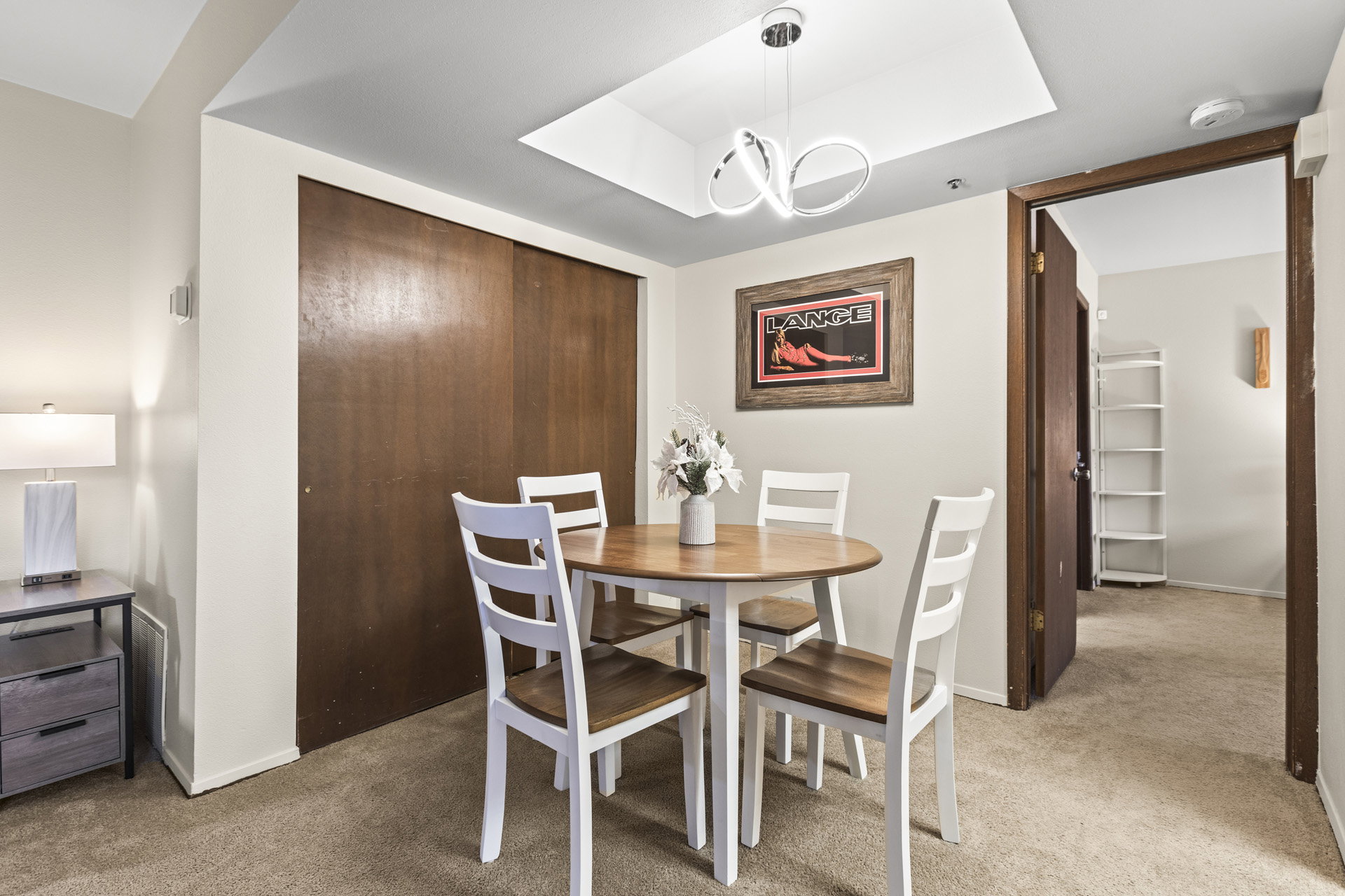 Dining area featuring carpet flooring, recessed ceiling with a contemporary light fixture, and a built-in closet with wood-finish sliding doors