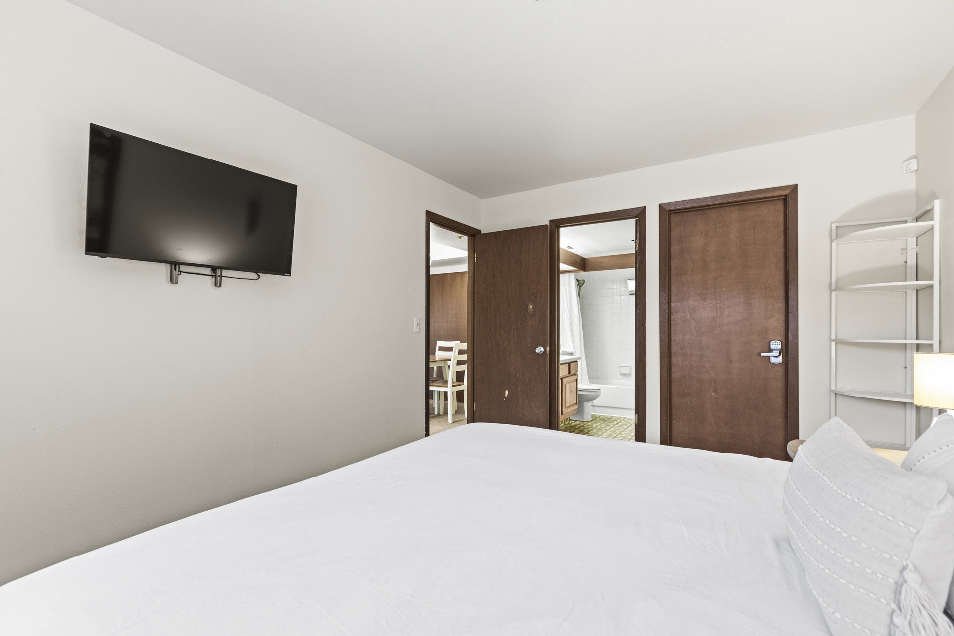 White walls with a mounted television and wood-finish doors