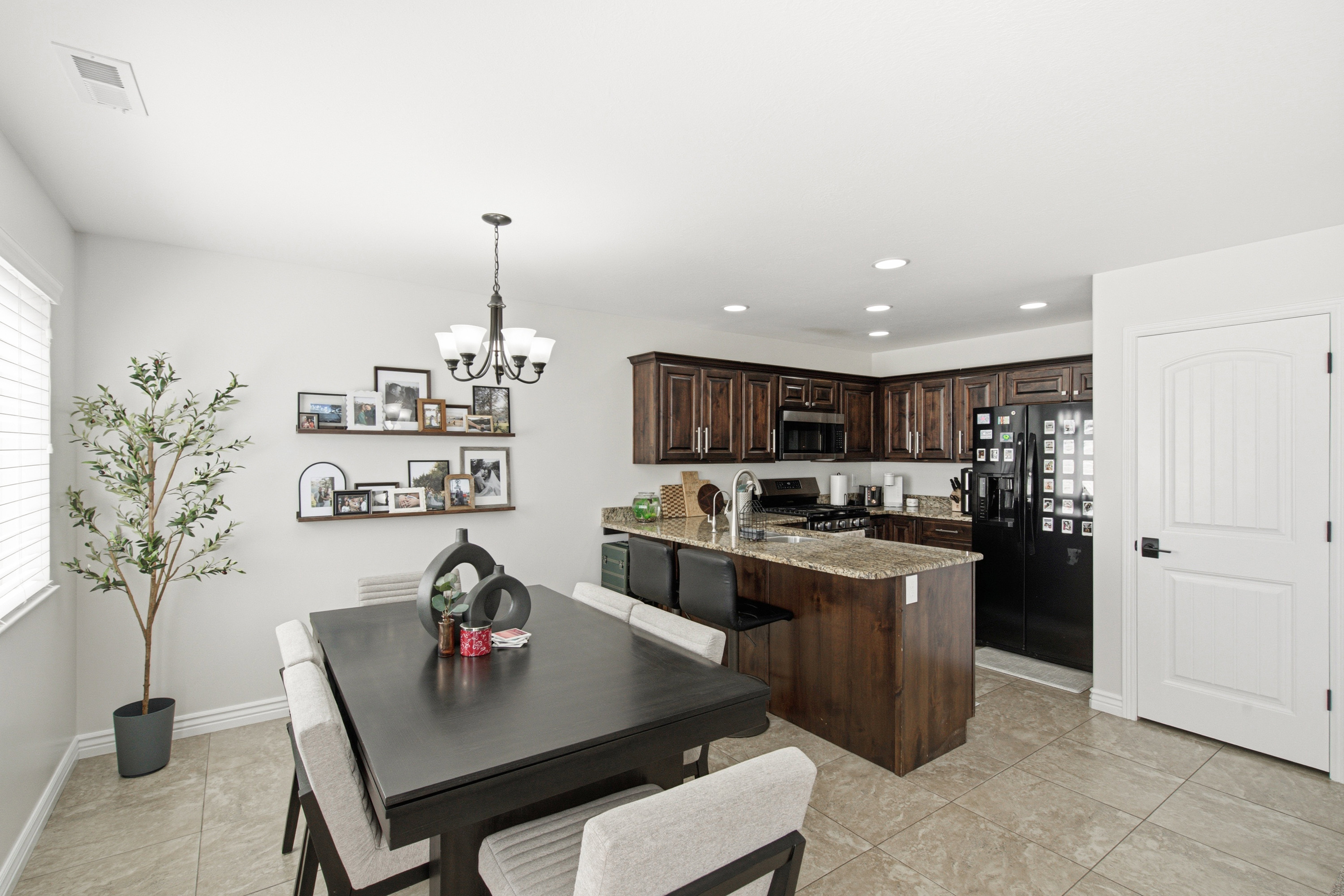 Open-concept kitchen and dining area featuring warm wood cabinetry, granite countertops, and a central island with bar seating