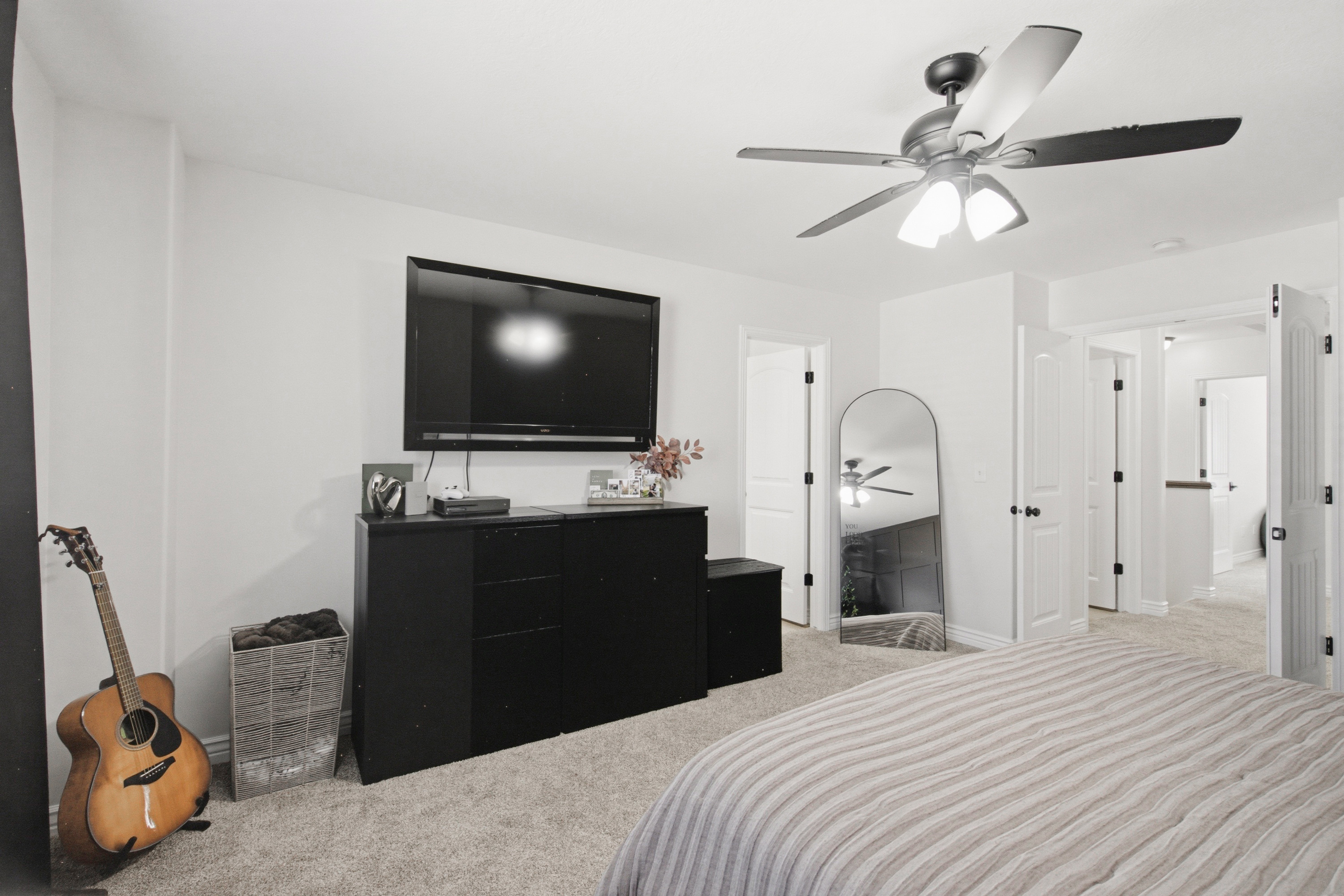 Carpeted room with a ceiling fan light fixture and multiple white panel doors