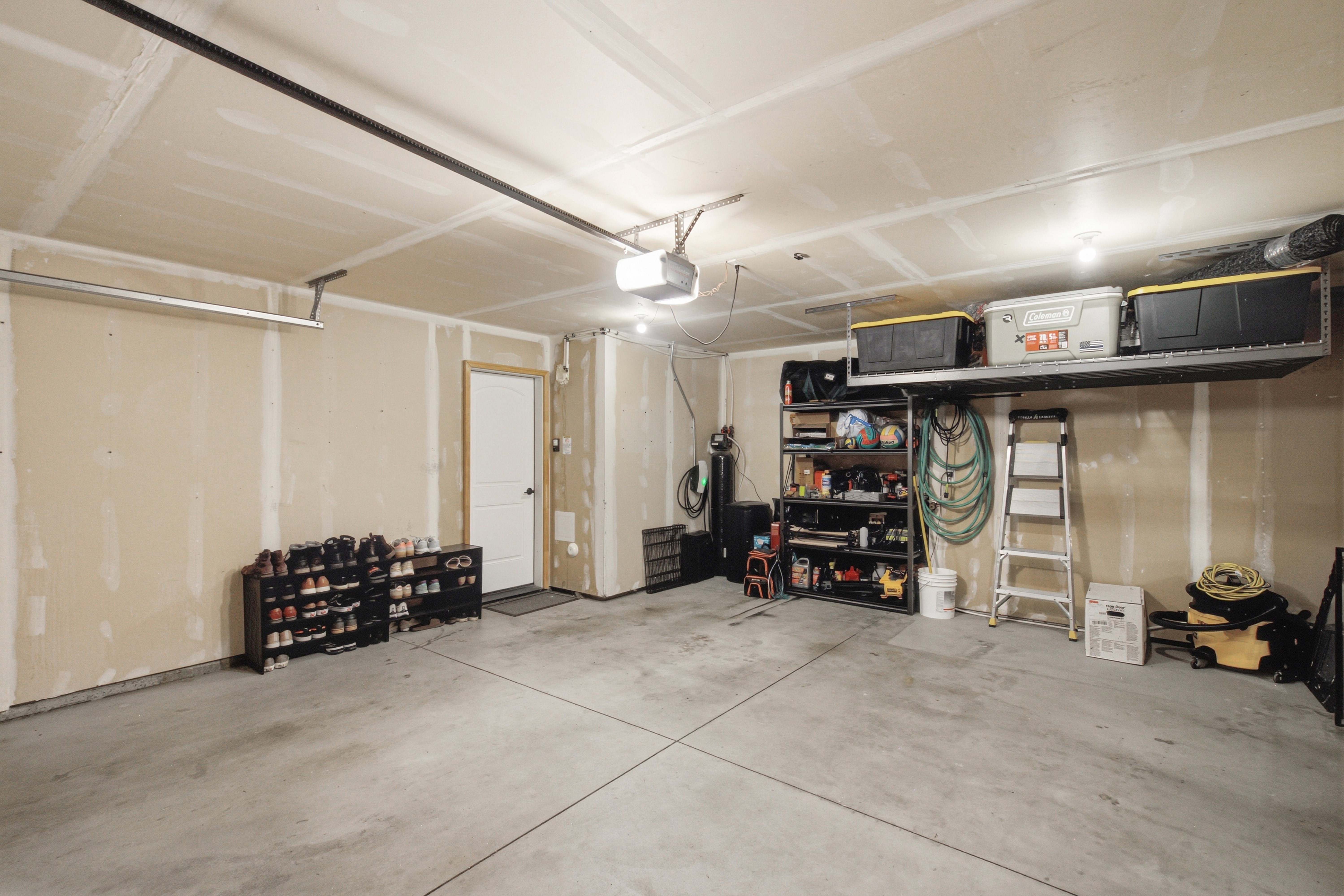 Attached garage featuring an automatic opener, exposed drywall, concrete flooring, and a side access door