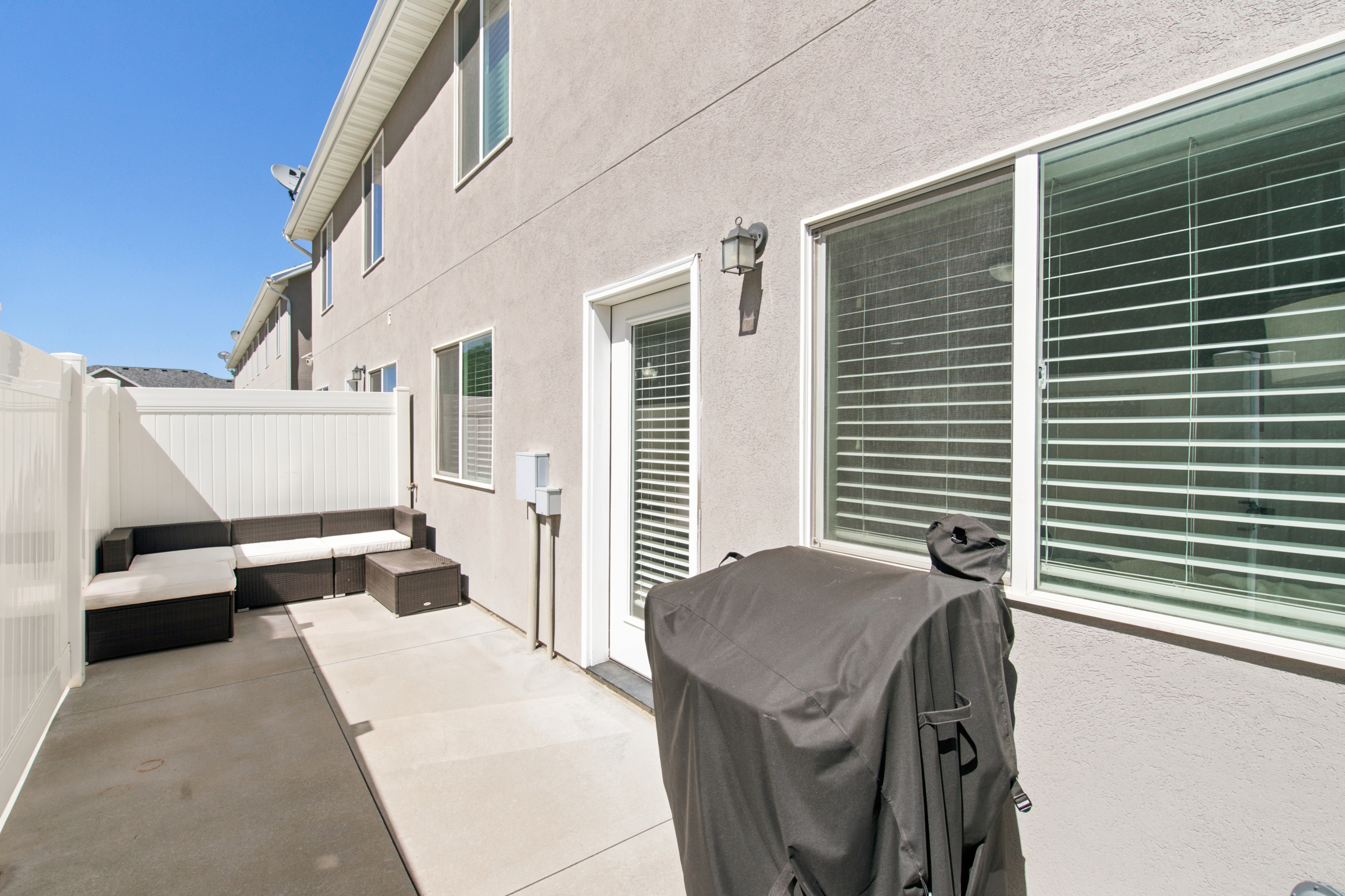 Private concrete patio featuring a white vinyl fence and a ground-level exterior door