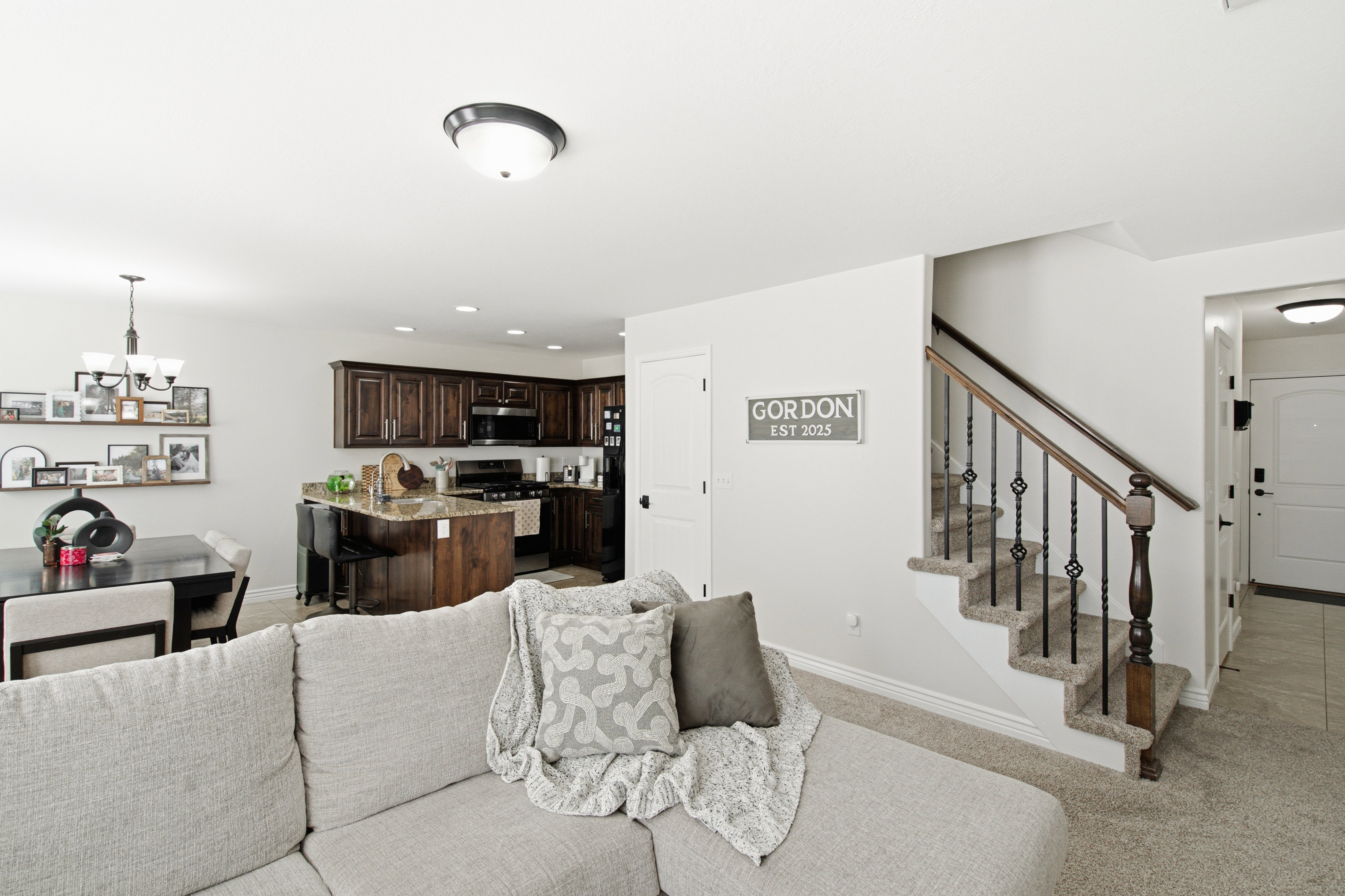 Open-concept living area with a dark wood kitchen featuring an island with stone countertops