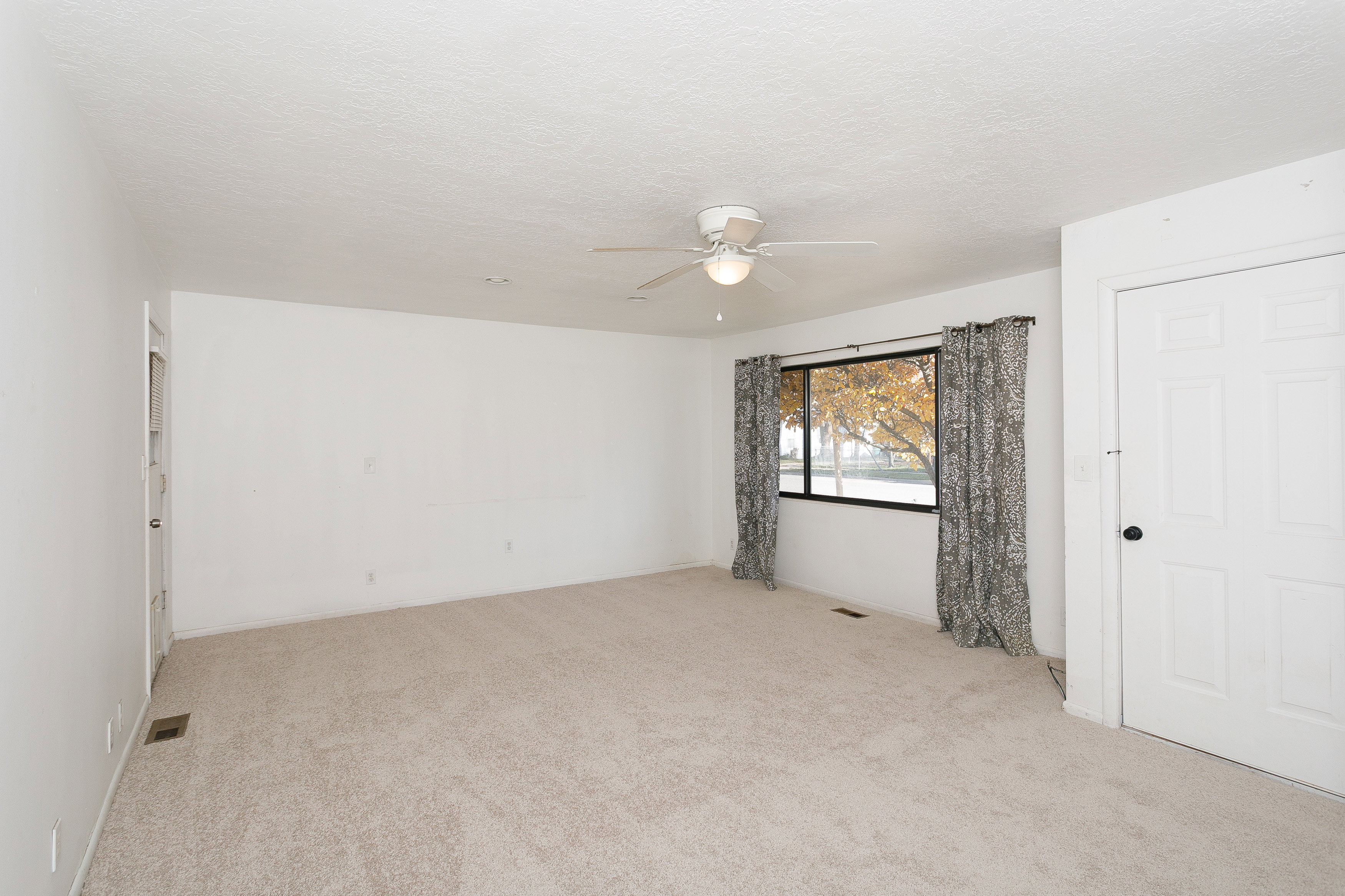Carpeted room featuring a ceiling fan with integrated lighting, a multi-pane window, and a paneled interior door