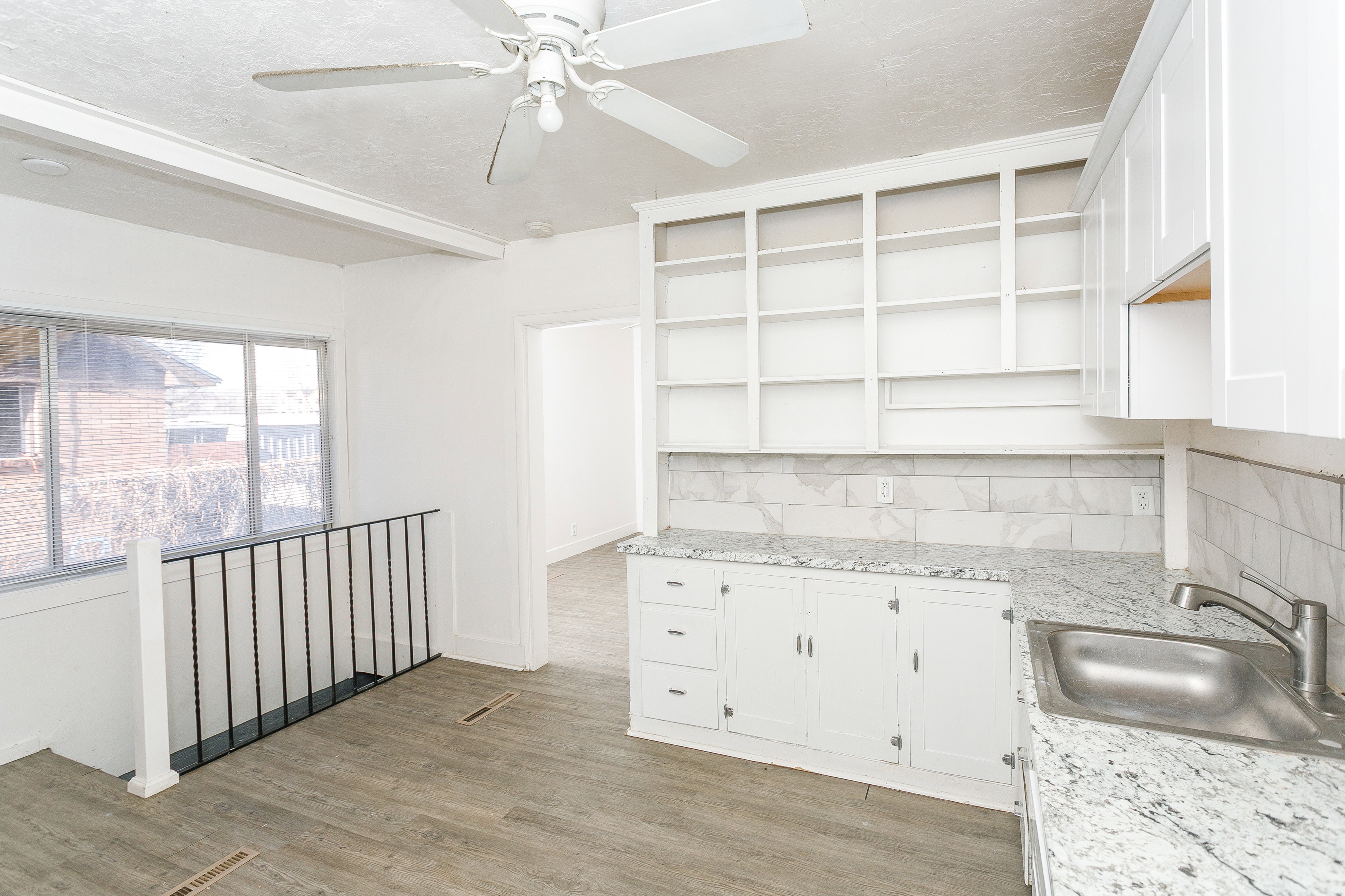 Kitchenette area featuring white cabinetry, light-colored countertops, a stainless steel sink, and a tile backsplash