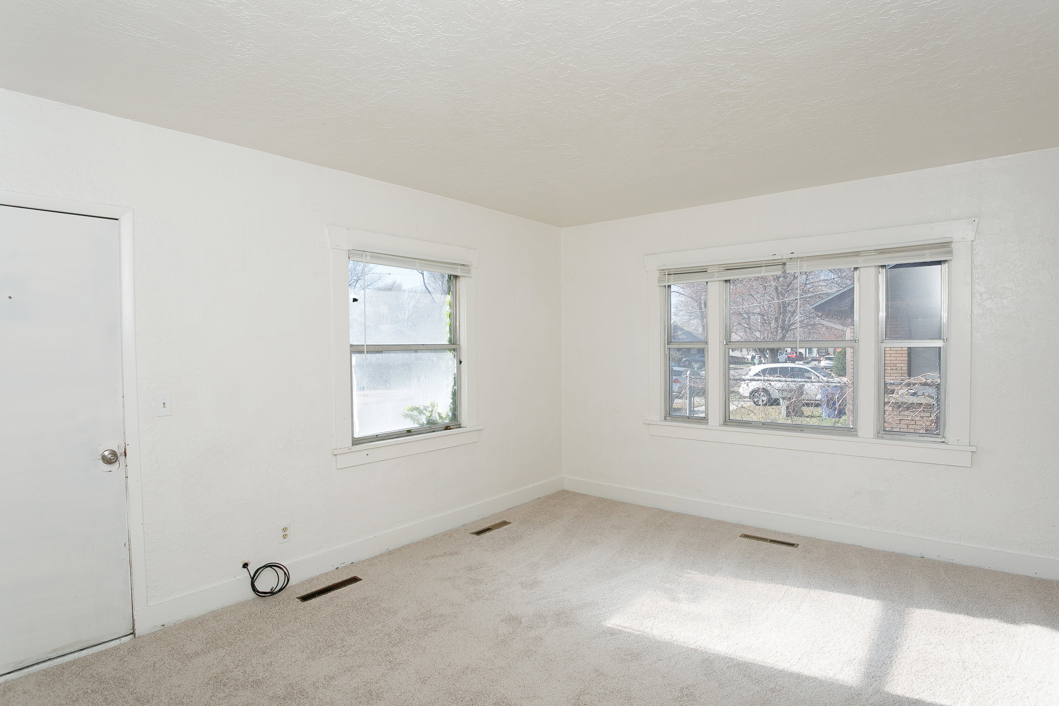 Carpeted room with white walls, featuring a multi-pane window and a single window with white trim