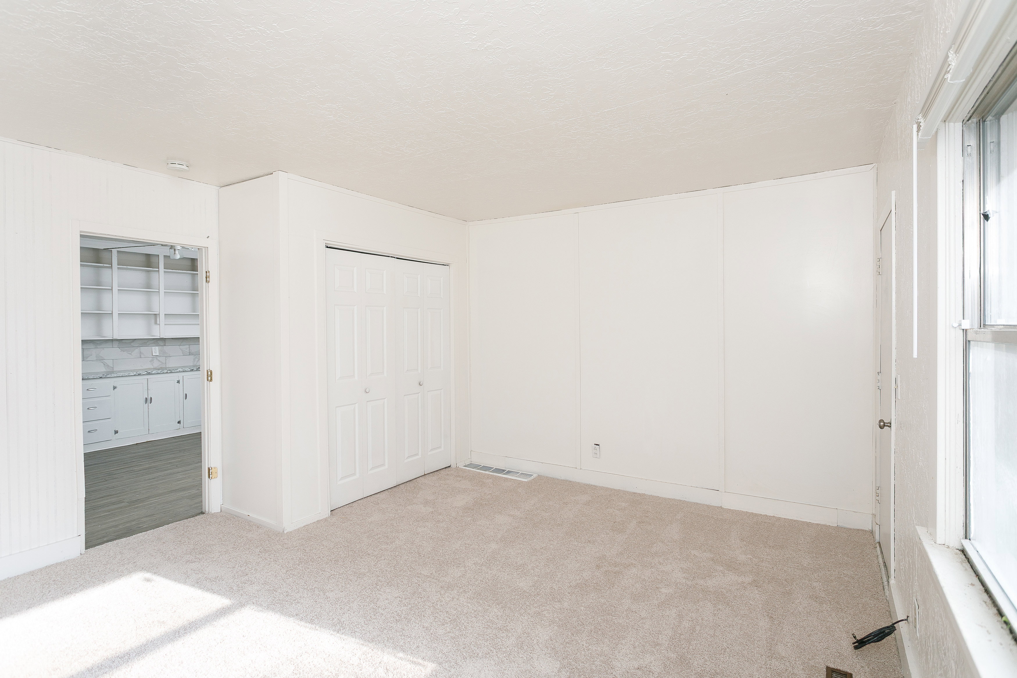 Room featuring light-toned carpet flooring and paneling walls