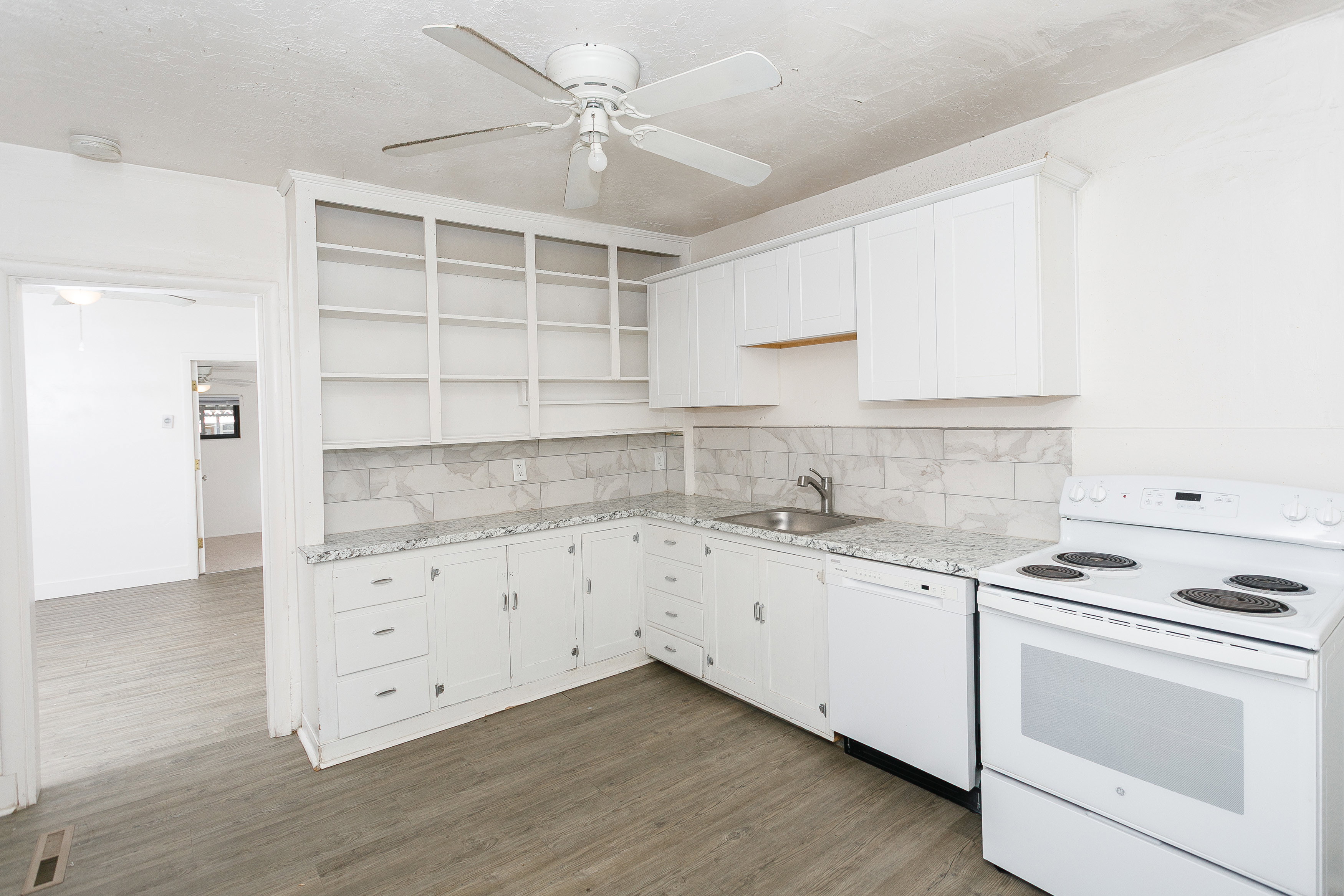 Kitchen featuring white cabinetry, granite-look countertops, subway tile backsplash, and wood-finish flooring
