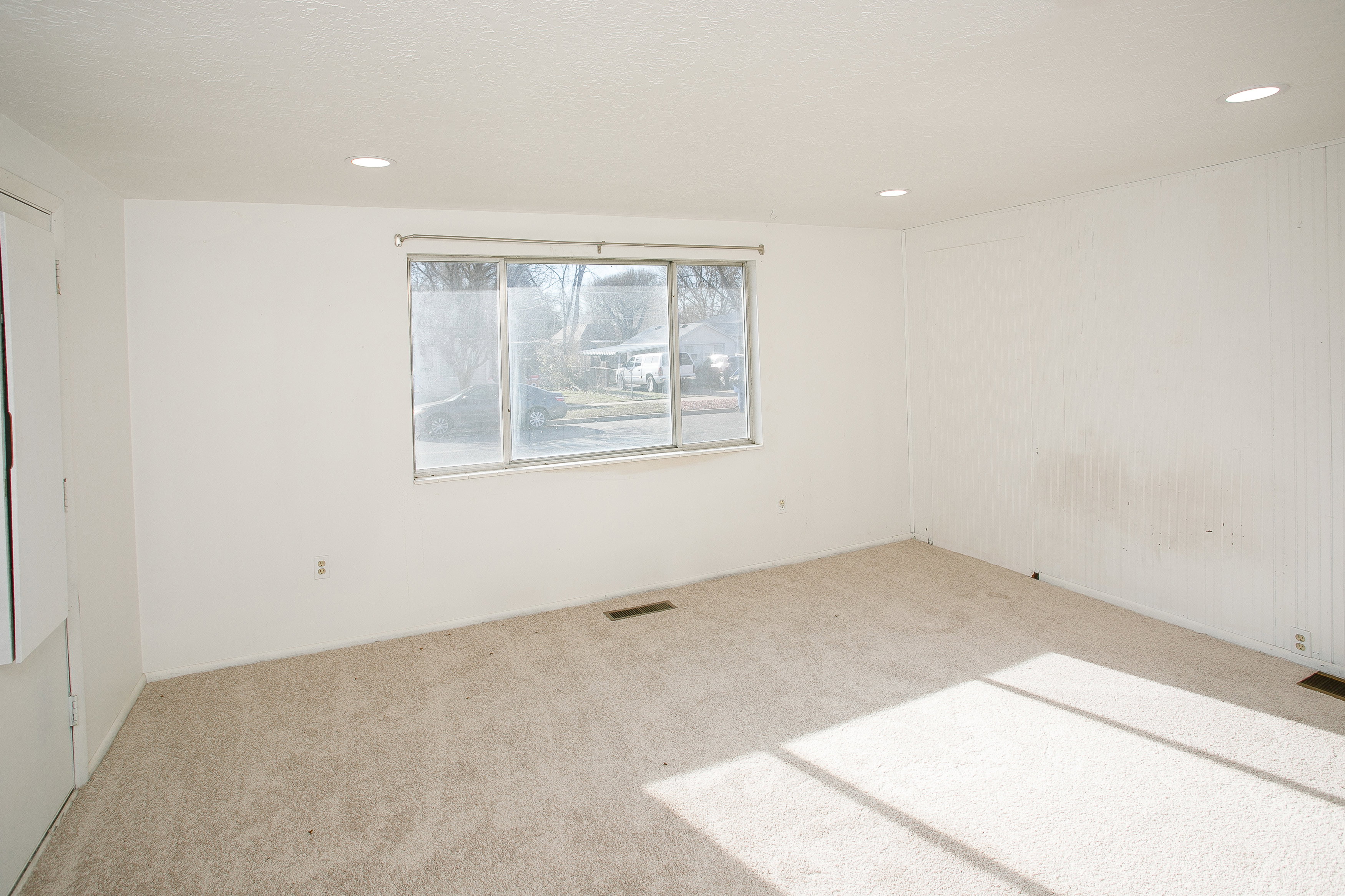 Spacious room with plush carpeting, recessed ceiling lighting, and a large window