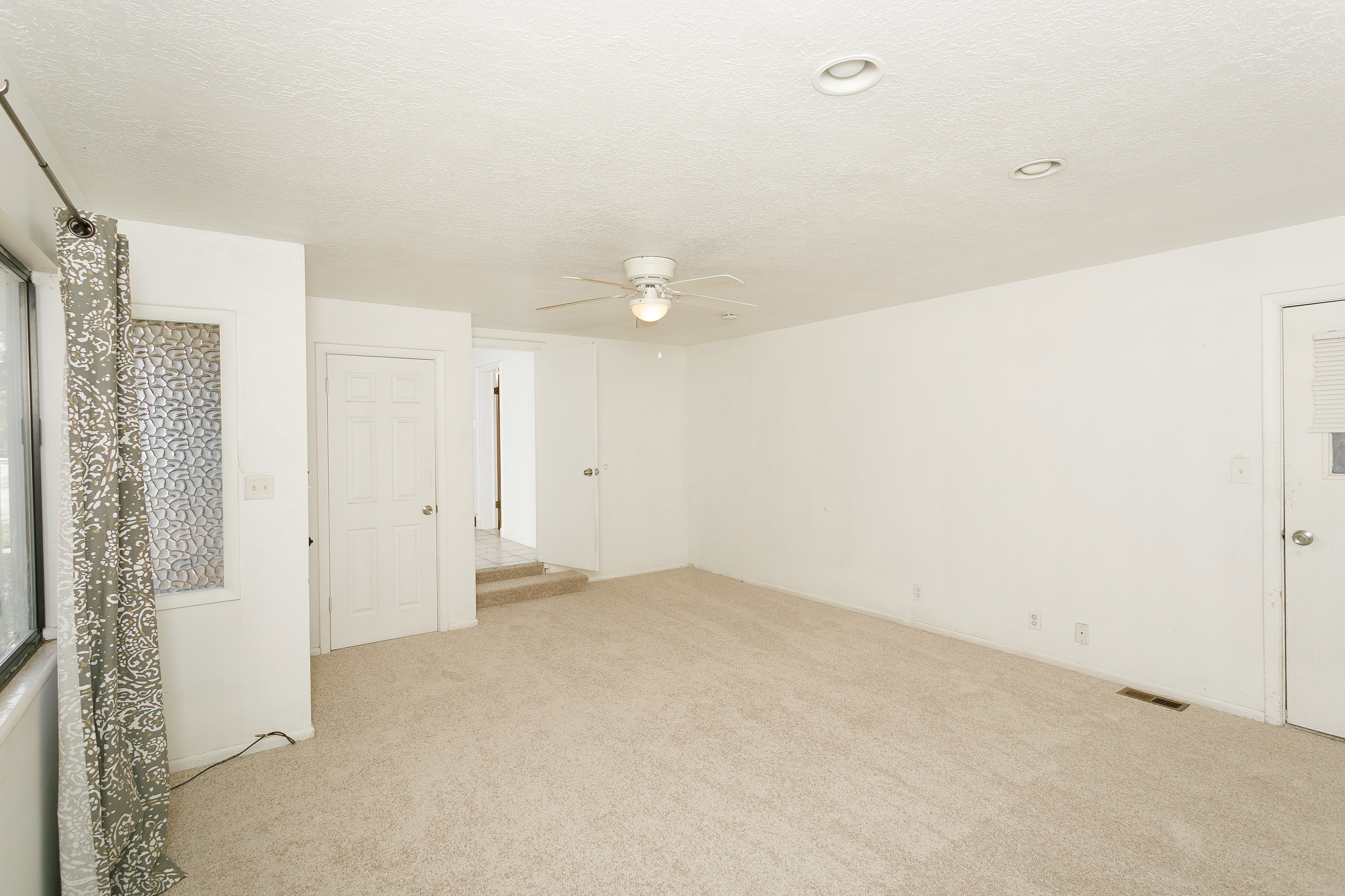 Spacious room featuring neutral carpeting, a ceiling fan with integrated lighting, and recessed ceiling lights