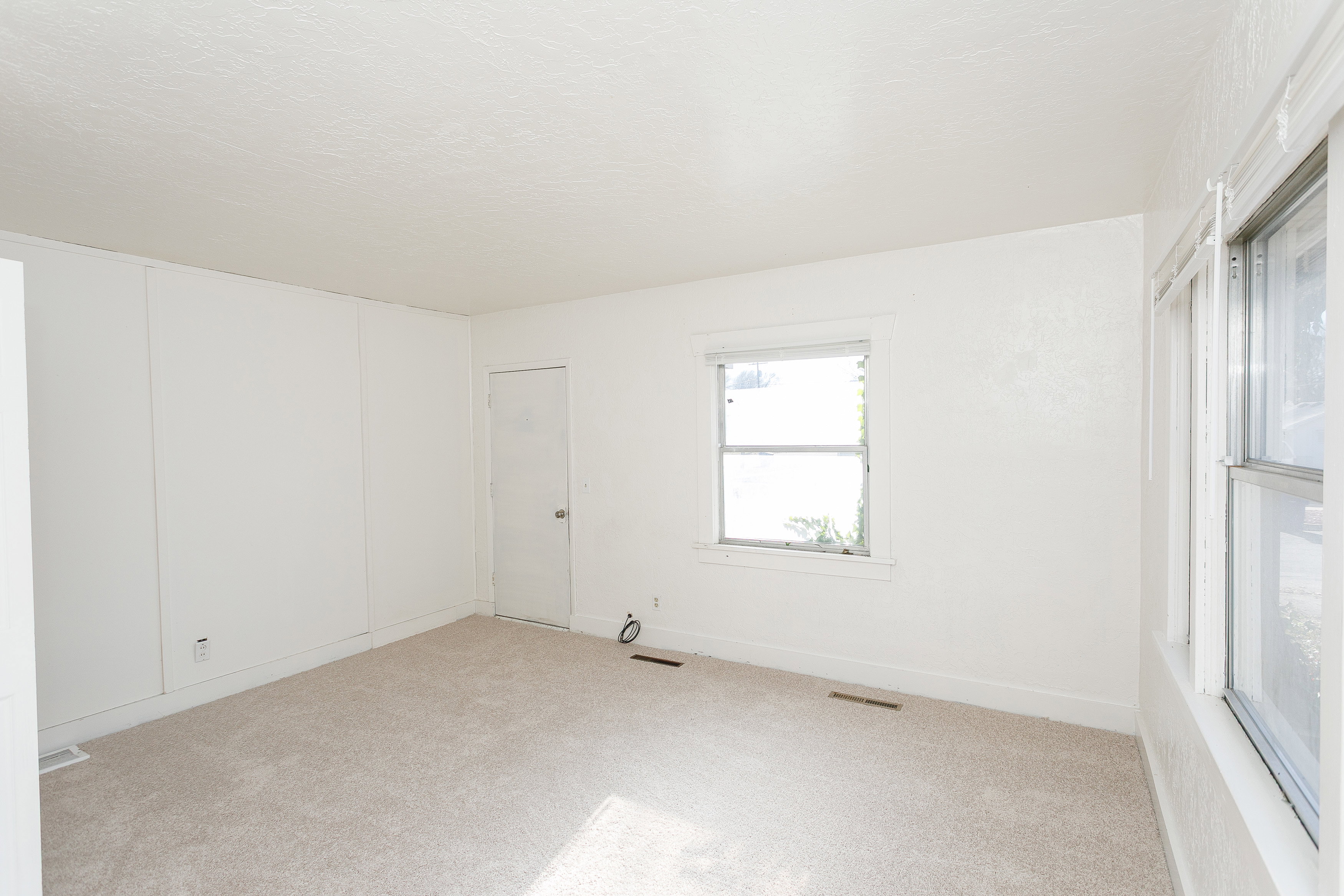 Carpeted interior room with white painted walls