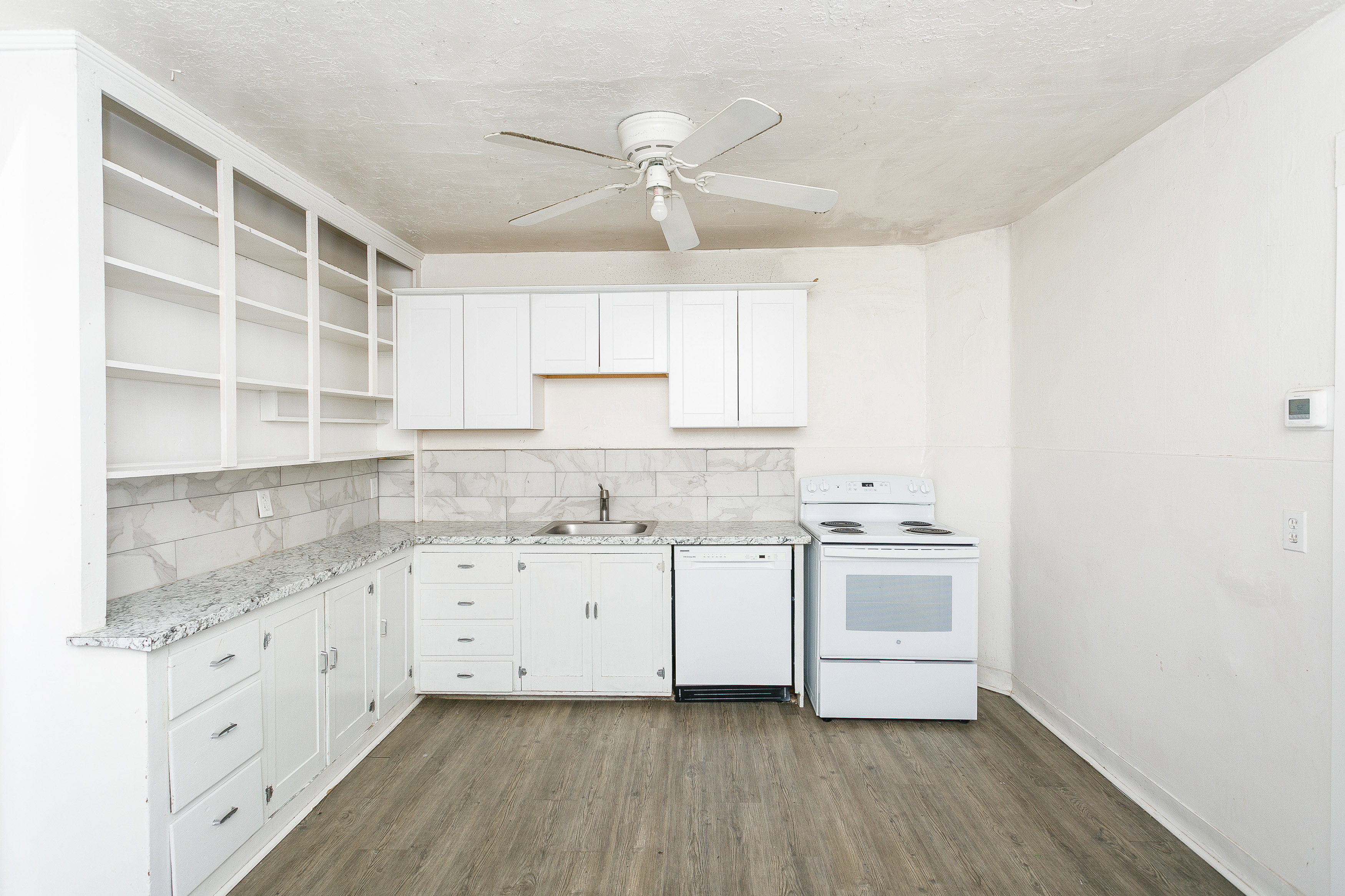 Kitchen featuring white cabinetry, granite-style countertops, and a subway tile backsplash