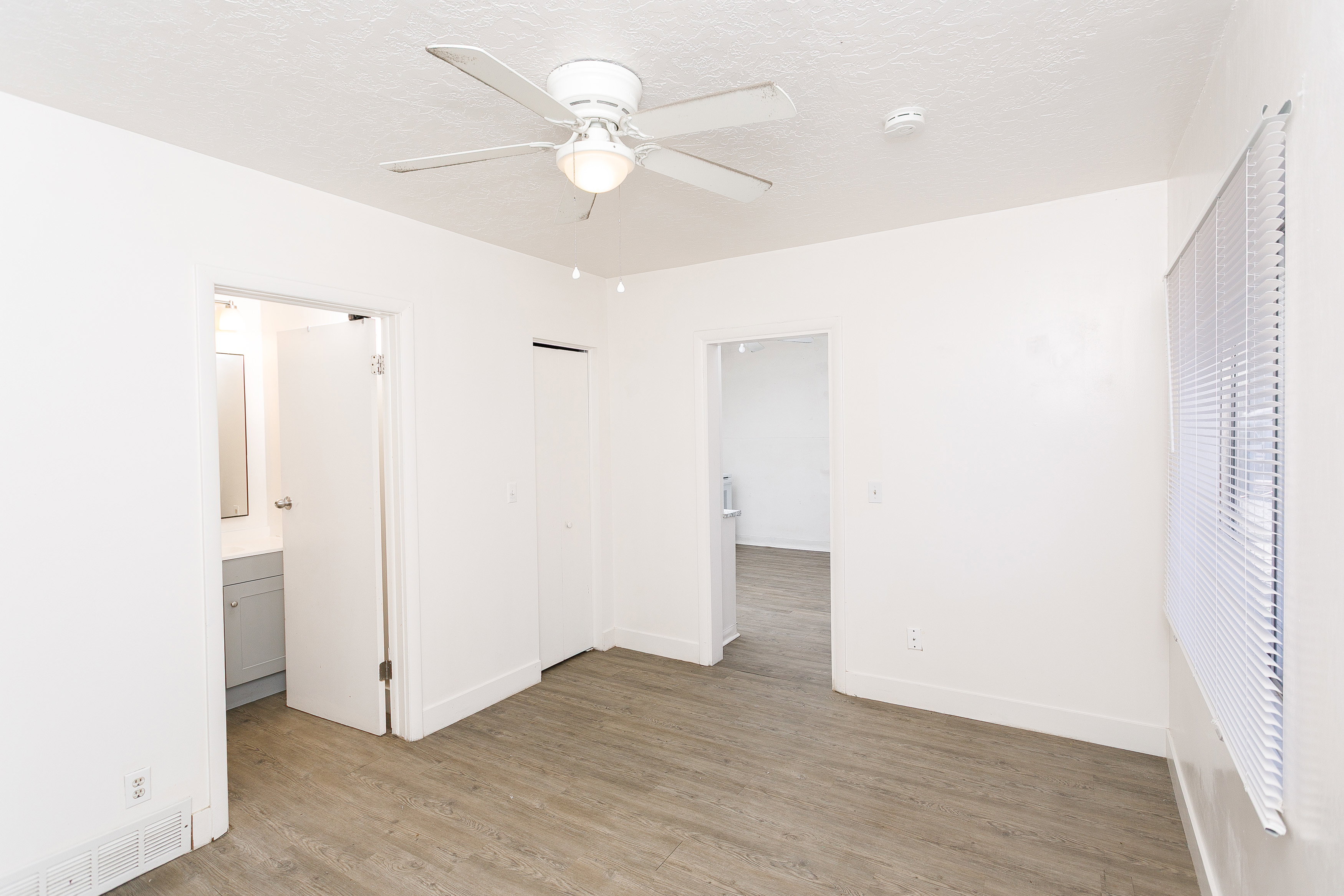 Bright interior room featuring wood-finish flooring and a ceiling fan with integrated lighting