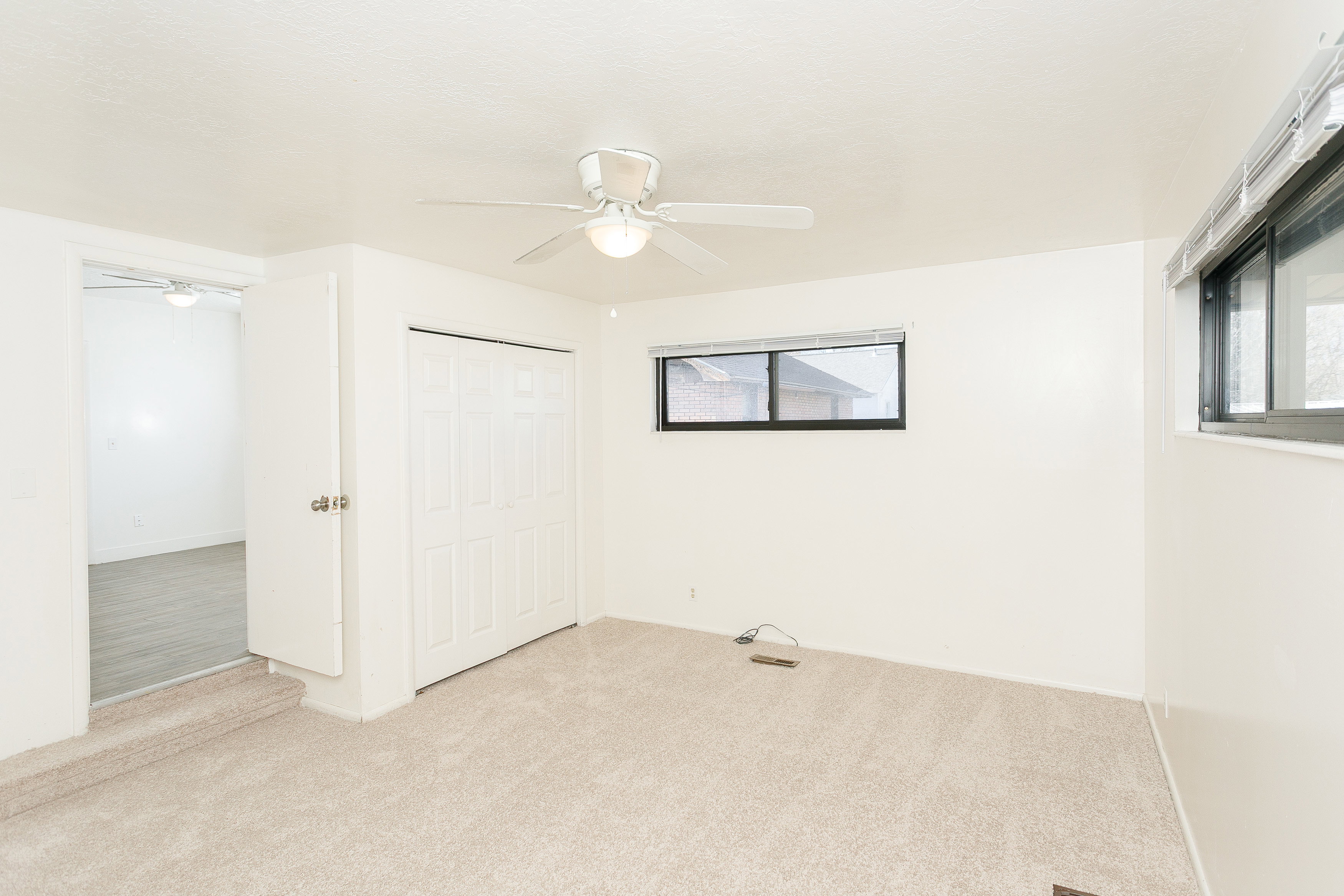 Carpeted room featuring a ceiling fan with integrated lighting, a bi-fold closet, and dual horizontal windows with blinds
