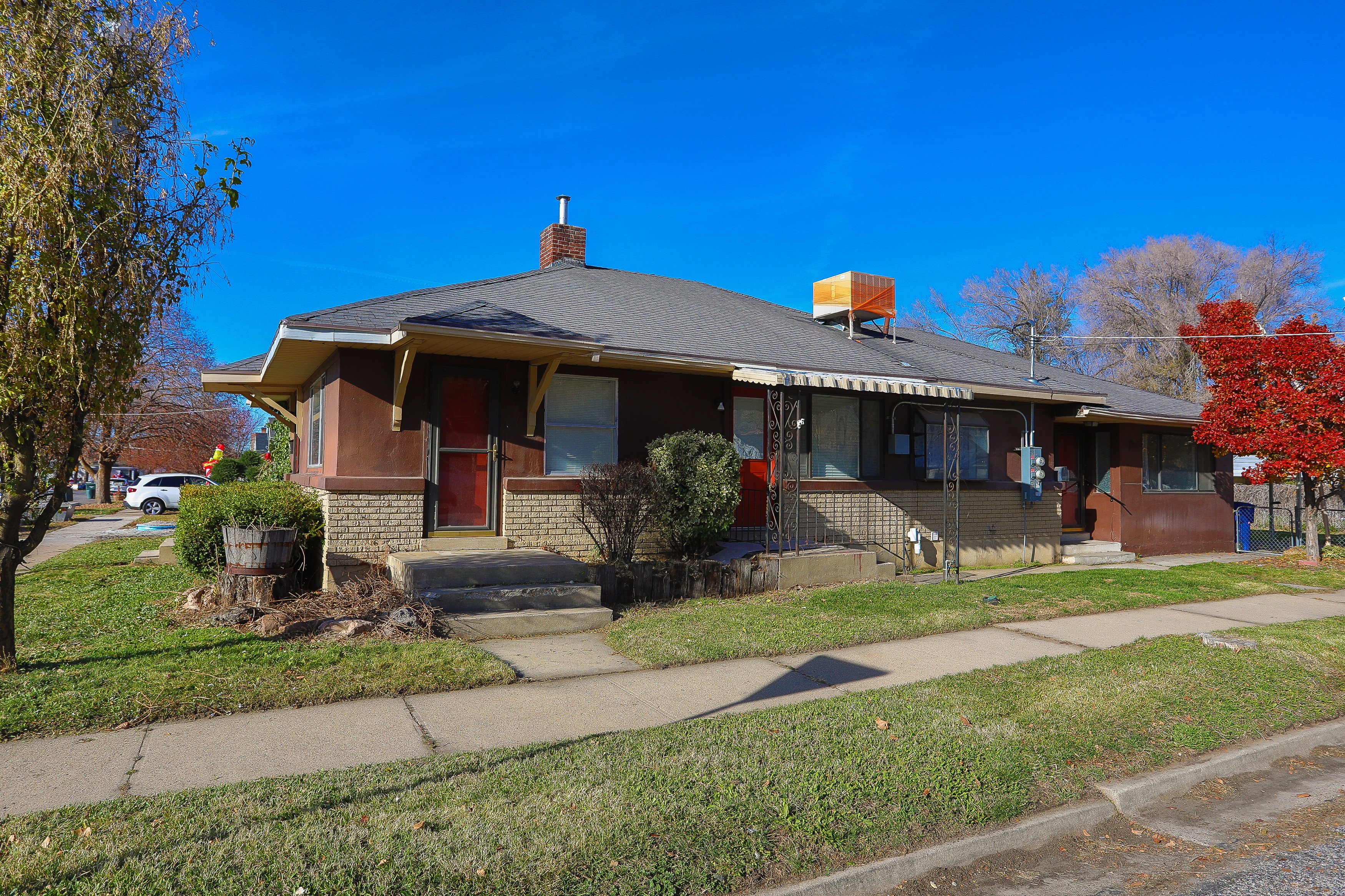 Brown multi-unit building featuring a brick chimney and a gabled roofline