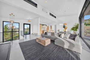 Spacious open-concept living area featuring high ceilings, wood-finish flooring, recessed lighting, and modern pendant light fixtures