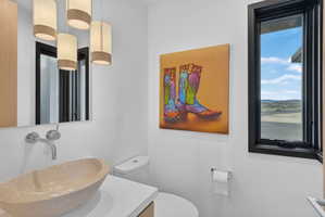 Modern powder room featuring a natural stone vessel sink, wall-mounted faucet, and a large mirror