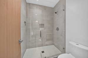 Walk-in shower featuring a frameless glass enclosure, large format tile walls, and a recessed niche