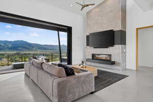Spacious living area featuring a large sliding glass door, mountain scenery, a floor-to-ceiling tile fireplace, high ceilings, and polished concrete flooring