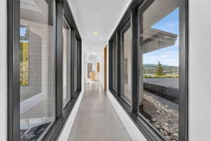 Hallway featuring a polished concrete floor, recessed lighting, and expansive windows with dark frames