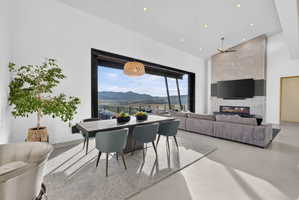 Open-concept living space with expansive floor-to-ceiling windows, modern gas fireplace with a stone-finish facade, recessed lighting, and a contemporary ceiling fan