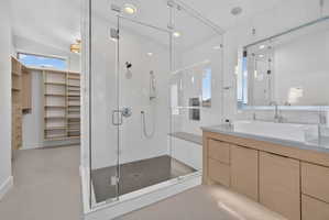 Spacious bathroom featuring a glass-enclosed shower with a built-in bench, a contemporary vanity with a vessel sink, and a large custom closet with extensive shelving