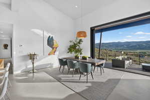 Spacious dining area featuring a vaulted ceiling, light-toned flooring, and a contemporary woven pendant light fixture
