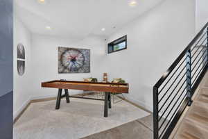 Lower-level recreation space featuring concrete flooring with an area rug, recessed lighting, and a window with a black frame