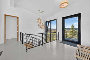 Upper landing featuring a black metal railing staircase, a full-light exterior door with a black frame, and a large fixed window