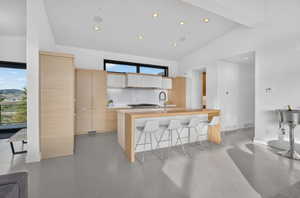 Modern kitchen featuring light wood-finish cabinetry, a central island with bar seating, and a white subway tile backsplash