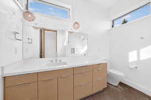 Modern bathroom featuring a long wood-finish vanity with ample storage and a white countertop