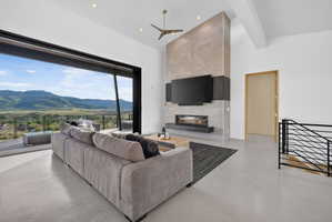 Expansive living space featuring a floor-to-ceiling fireplace with an integrated linear firebox, high ceilings with recessed lighting, and a modern ceiling fan