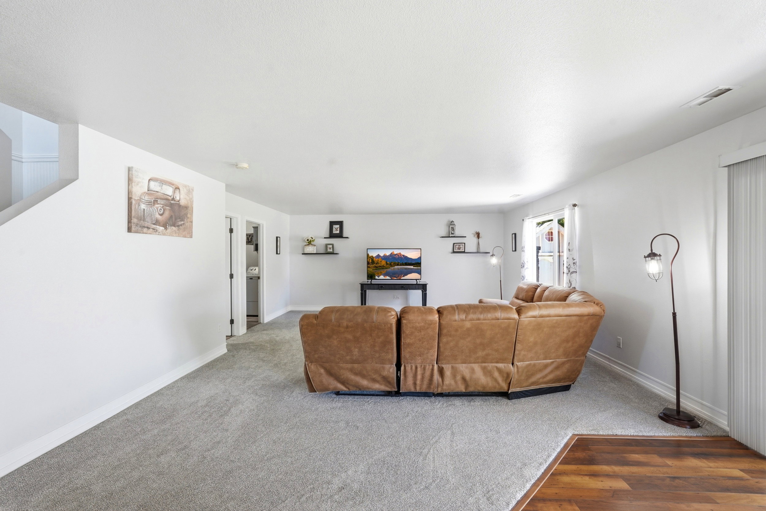 Open-concept living space featuring light gray carpeting and wood-finish flooring