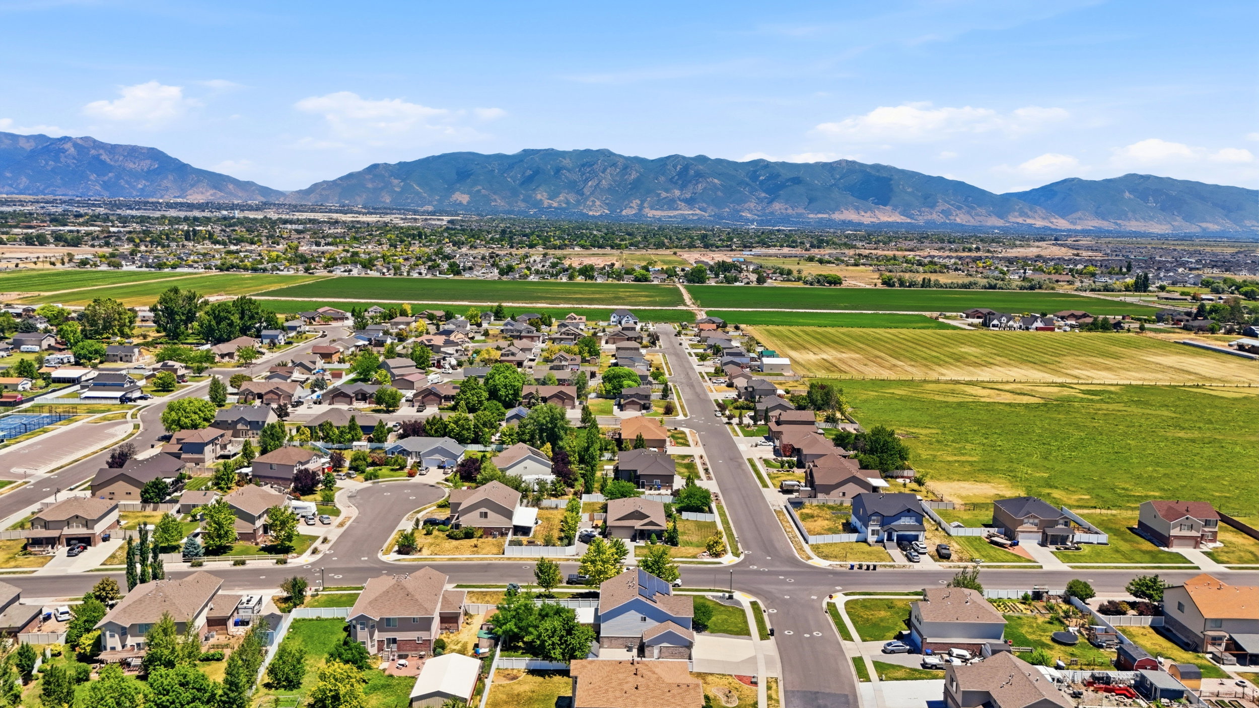 Aerial perspective showcasing a residential development with surrounding green fields and distant mountains