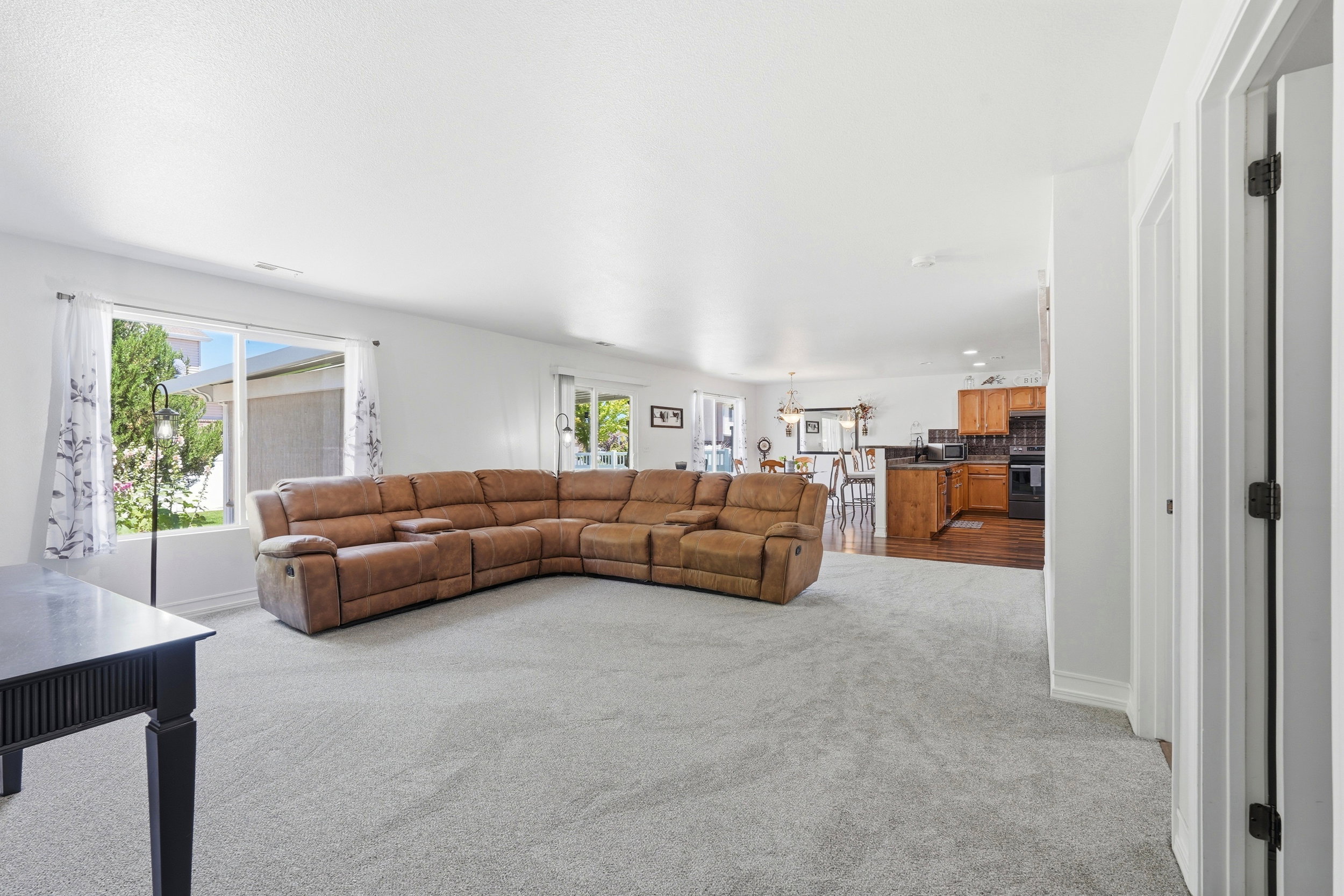 Spacious living area featuring light-toned carpeting and ample natural light from large windows